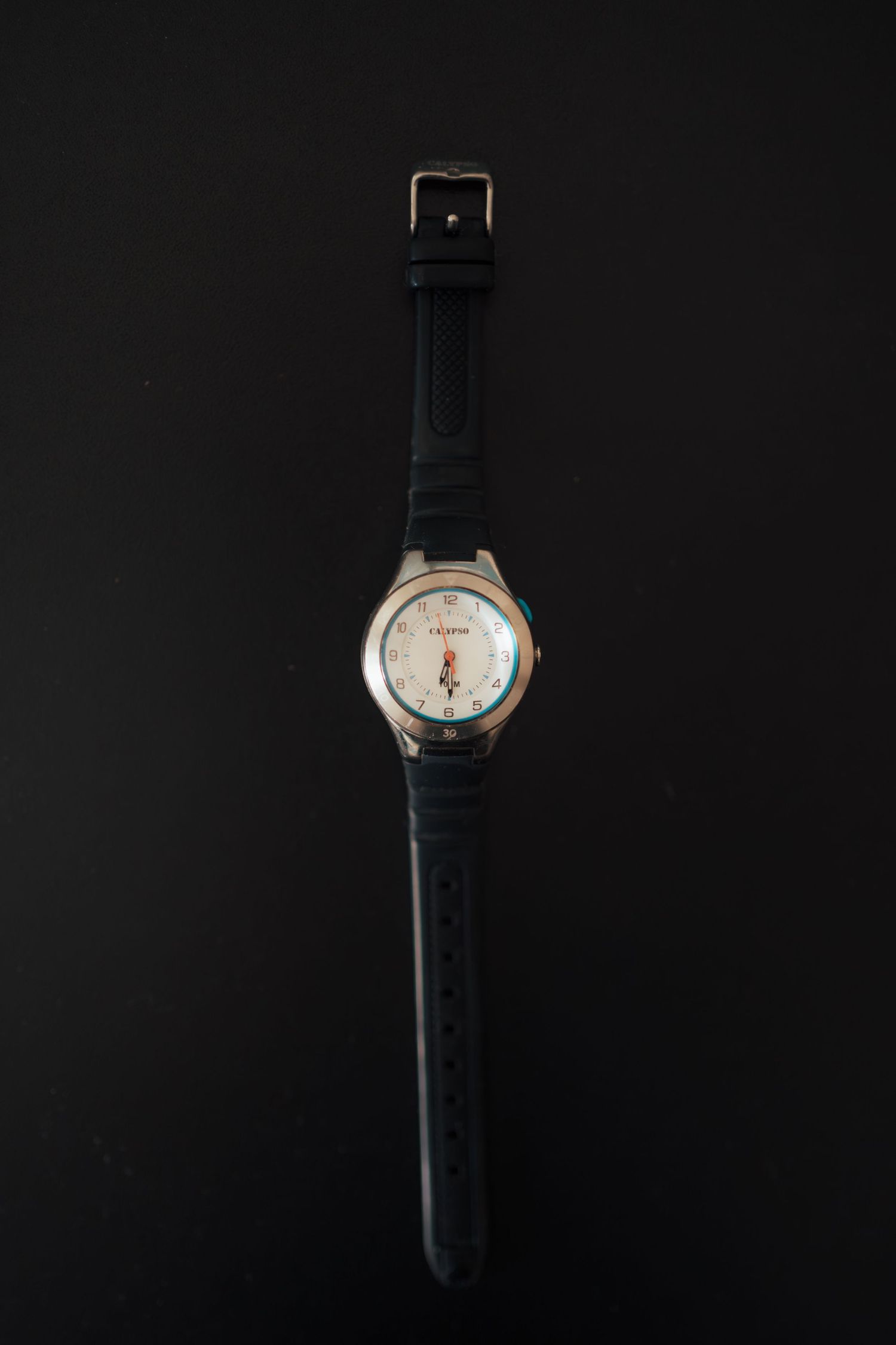 Classic wristwatch with black leather strap on dark background.