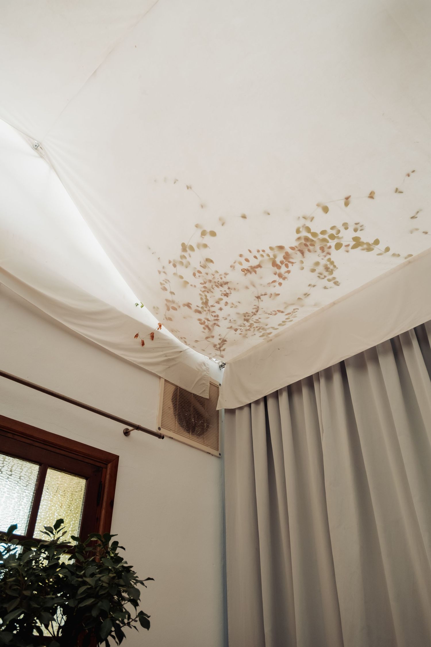 Water damage stains visible on white ceiling near curtain and air conditioning unit in wedding venue.