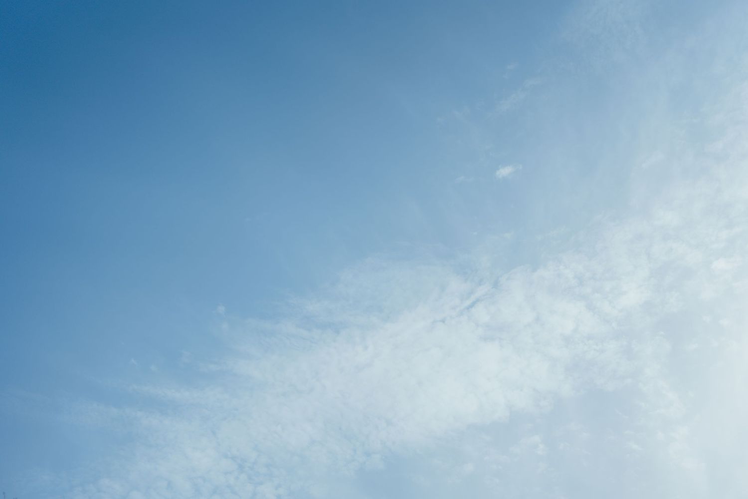 Clear blue sky with wispy white cirrus clouds on a sunny day.