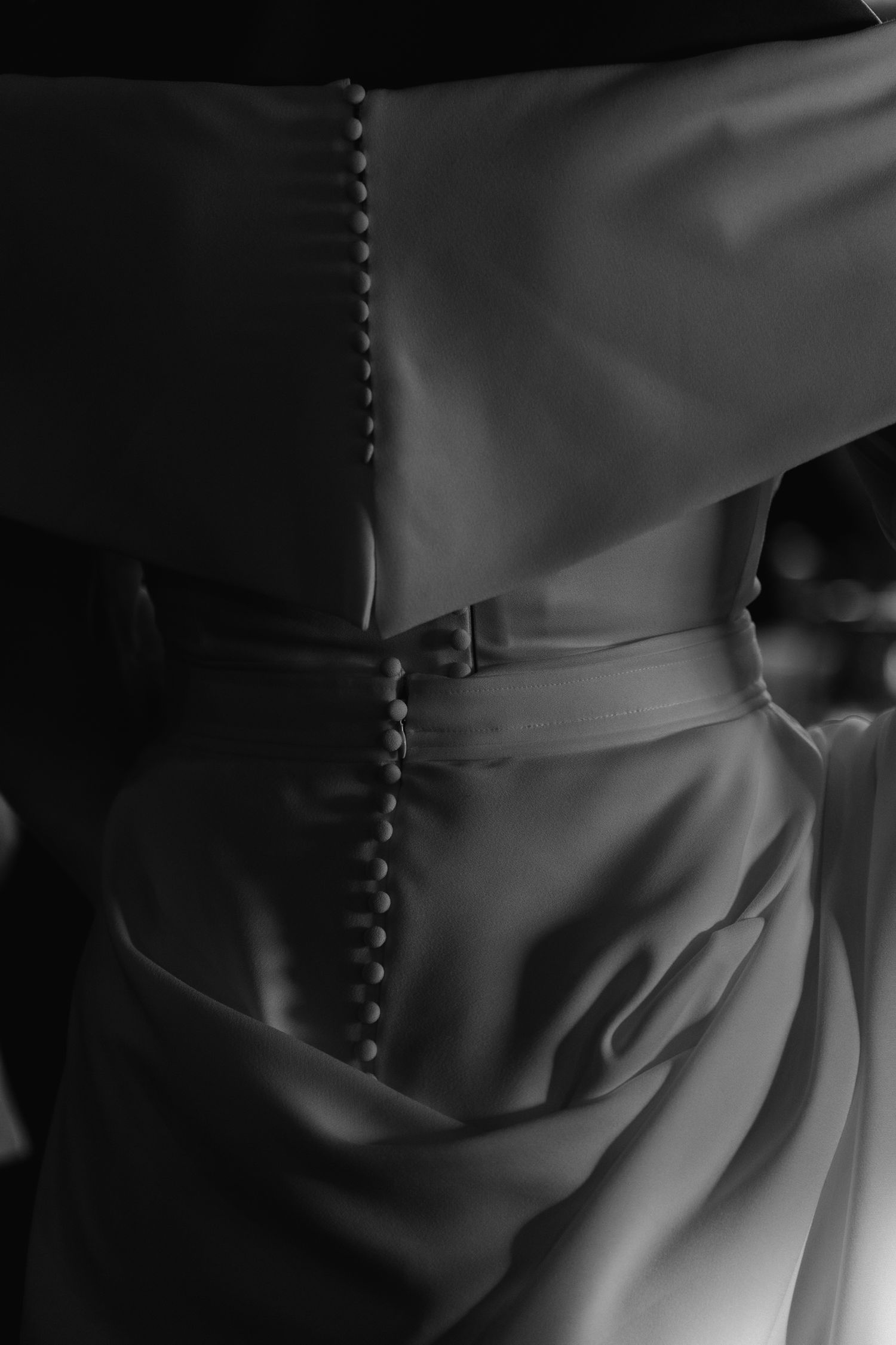 Close-up black and white detail of button-back wedding dress with belt.