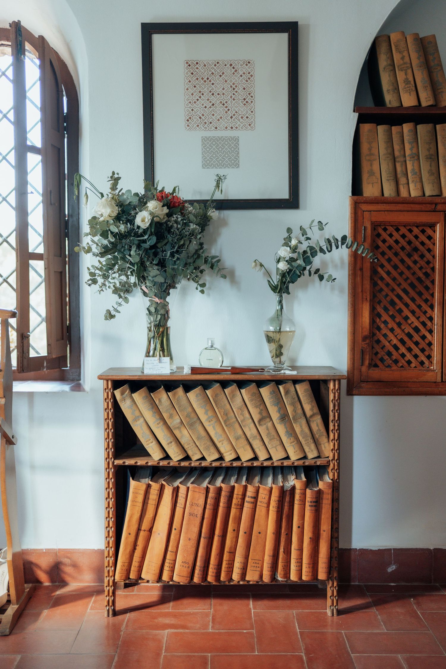 Vintage wooden bookshelf with antique books and floral arrangements in a rustic interior.