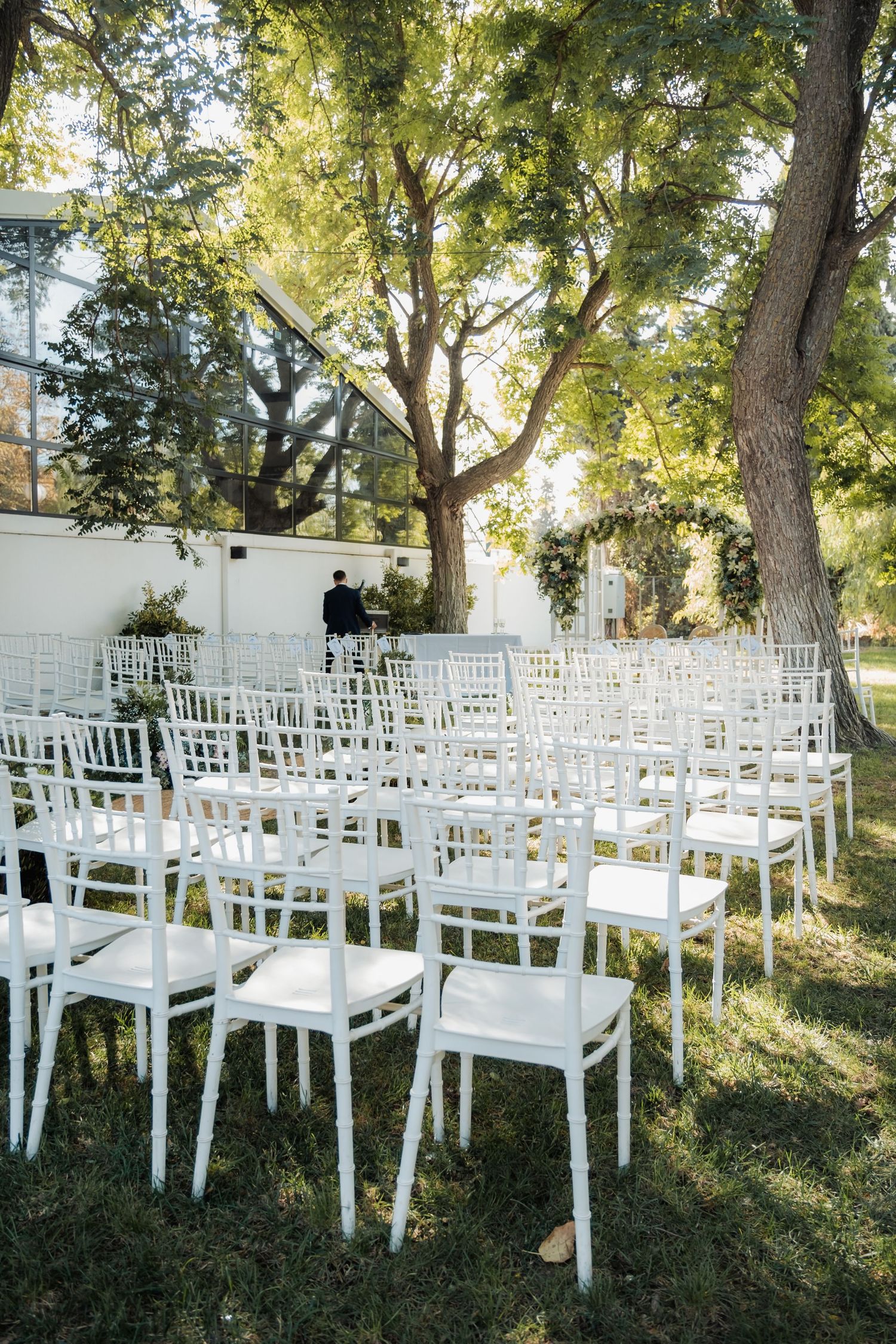 Rows of elegant white Chiavari chairs arranged on green lawn for an outdoor garden wedding ceremony.