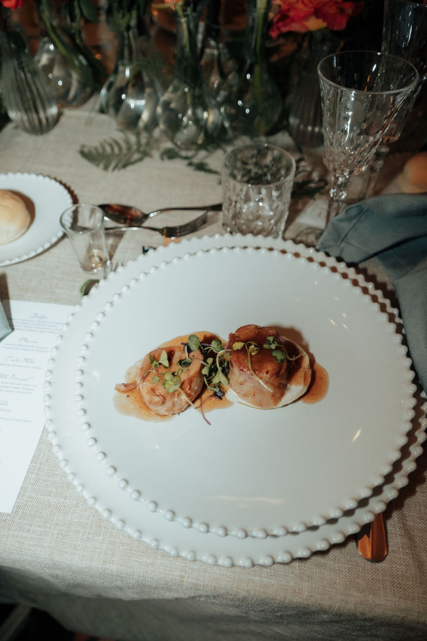 Elegant wedding reception plate with gourmet appetizer served on white beaded charger plate.
