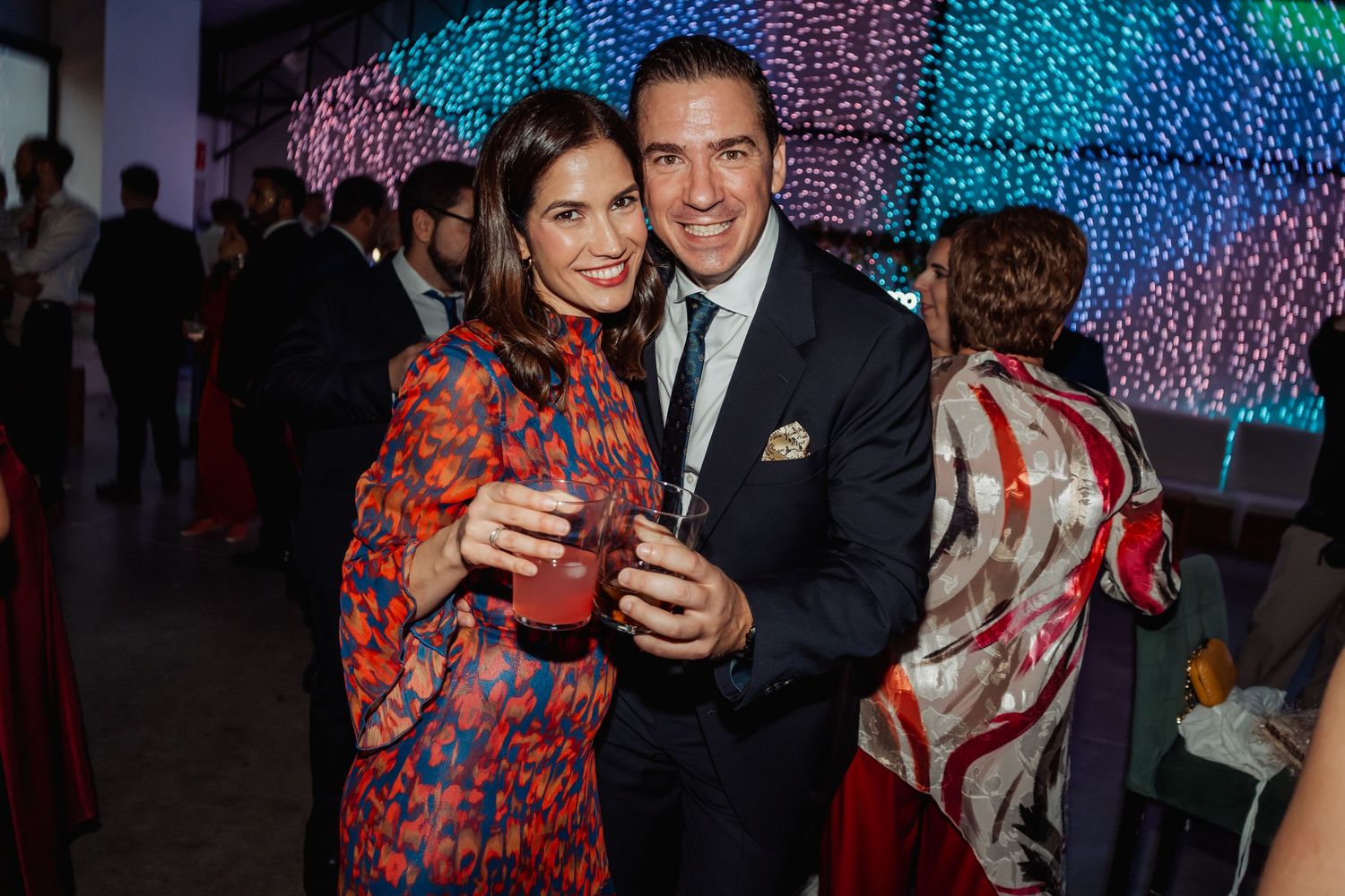 Elegant couple smiling and holding cocktails at a sophisticated evening celebration event.