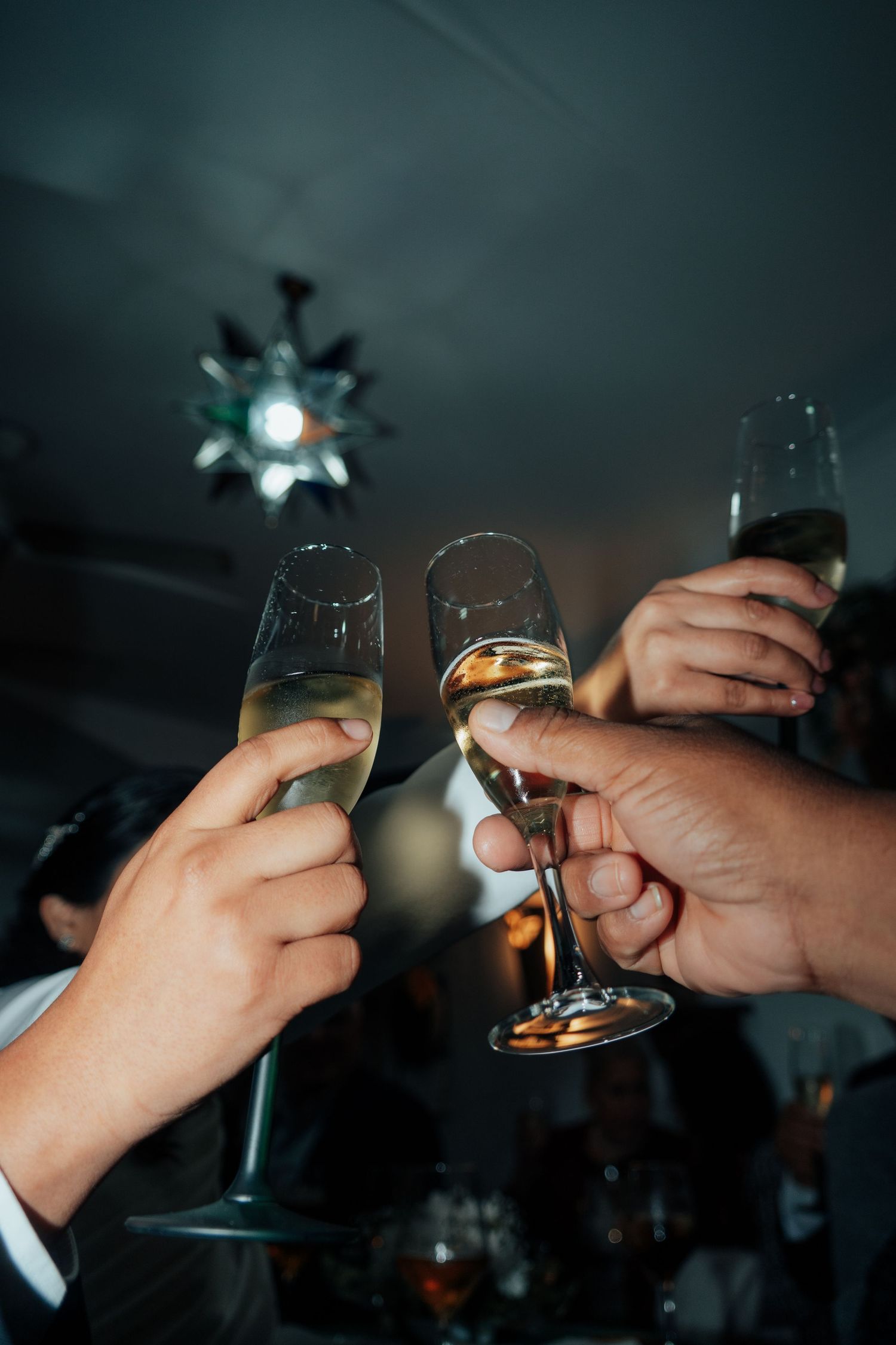 Hands clinking champagne flutes in a celebratory toast at an elegant evening party.