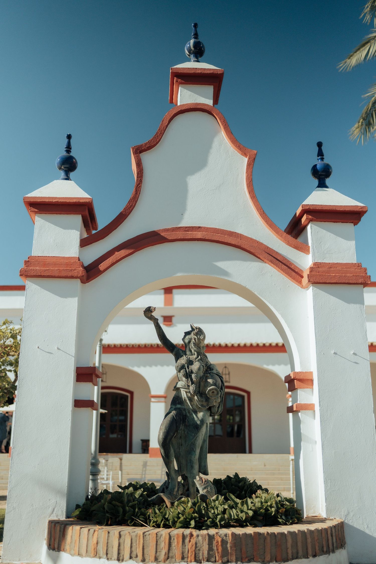 Bronze equestrian statue framed by a white and red ornate archway at a Spanish estate venue.