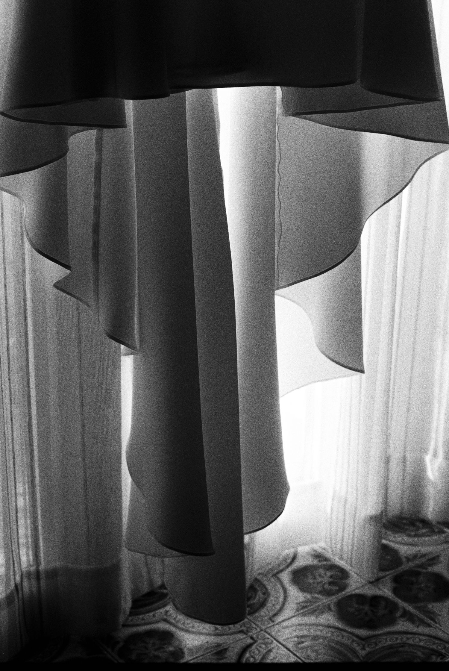 Artistic black and white photo of flowing bridal veil layers with light through sheer curtains.