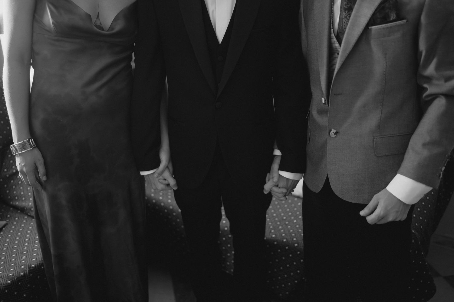 Black and white photo of three elegantly dressed wedding guests posing together at a formal event.