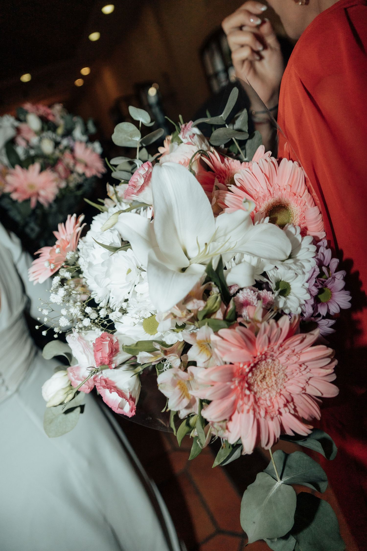 Bride holding beautiful wedding bouquet with pink gerbera daisies and white lilies.