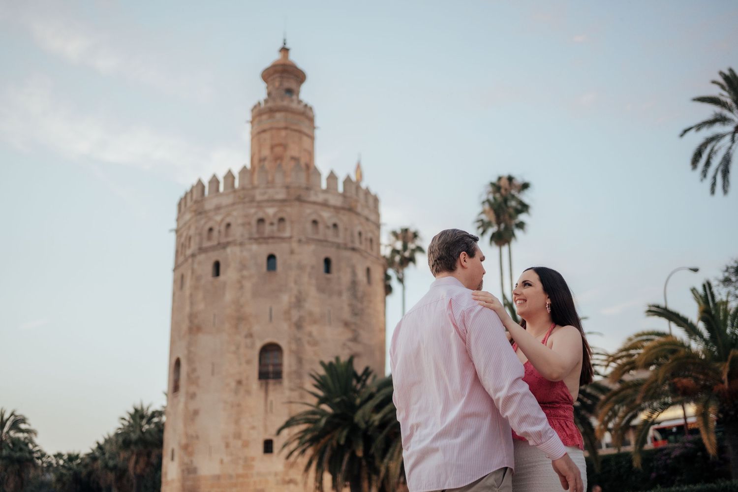 Couple posing romantically in front of the iconic Torre del Oro tower in Seville, Spain.