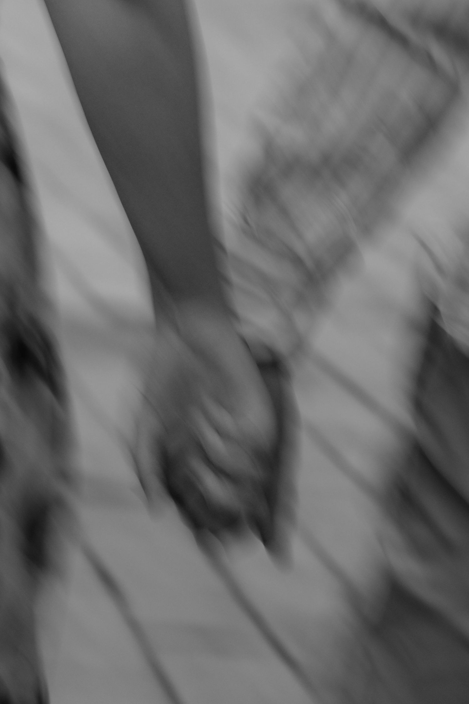 Artistic blurred black and white motion shot of couple holding hands outdoors.