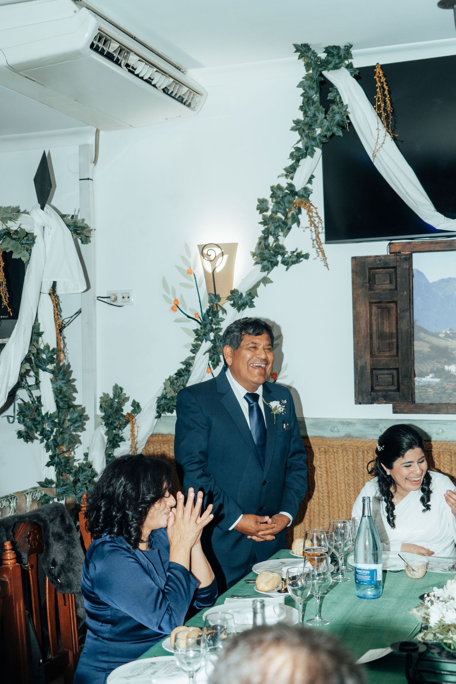 Father of the bride giving a heartfelt wedding speech at a decorated reception dinner table.