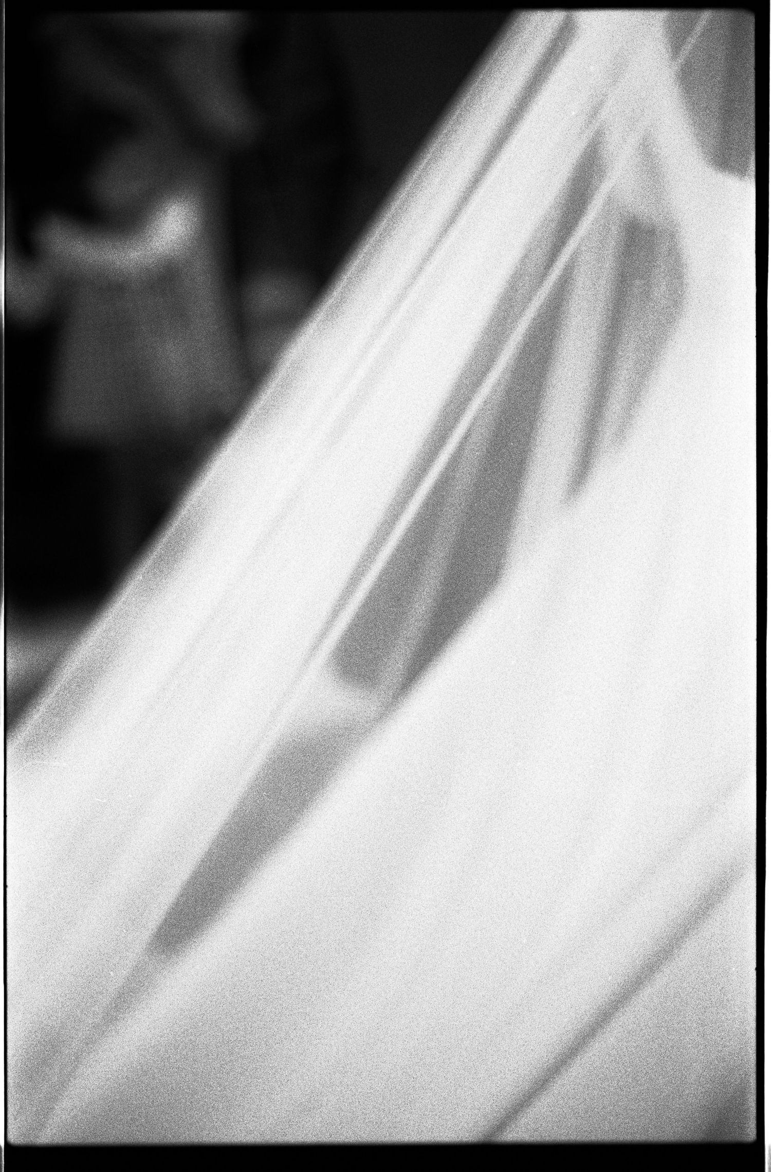 Close-up black and white abstract shot of flowing white bridal veil fabric with soft light and shadows.