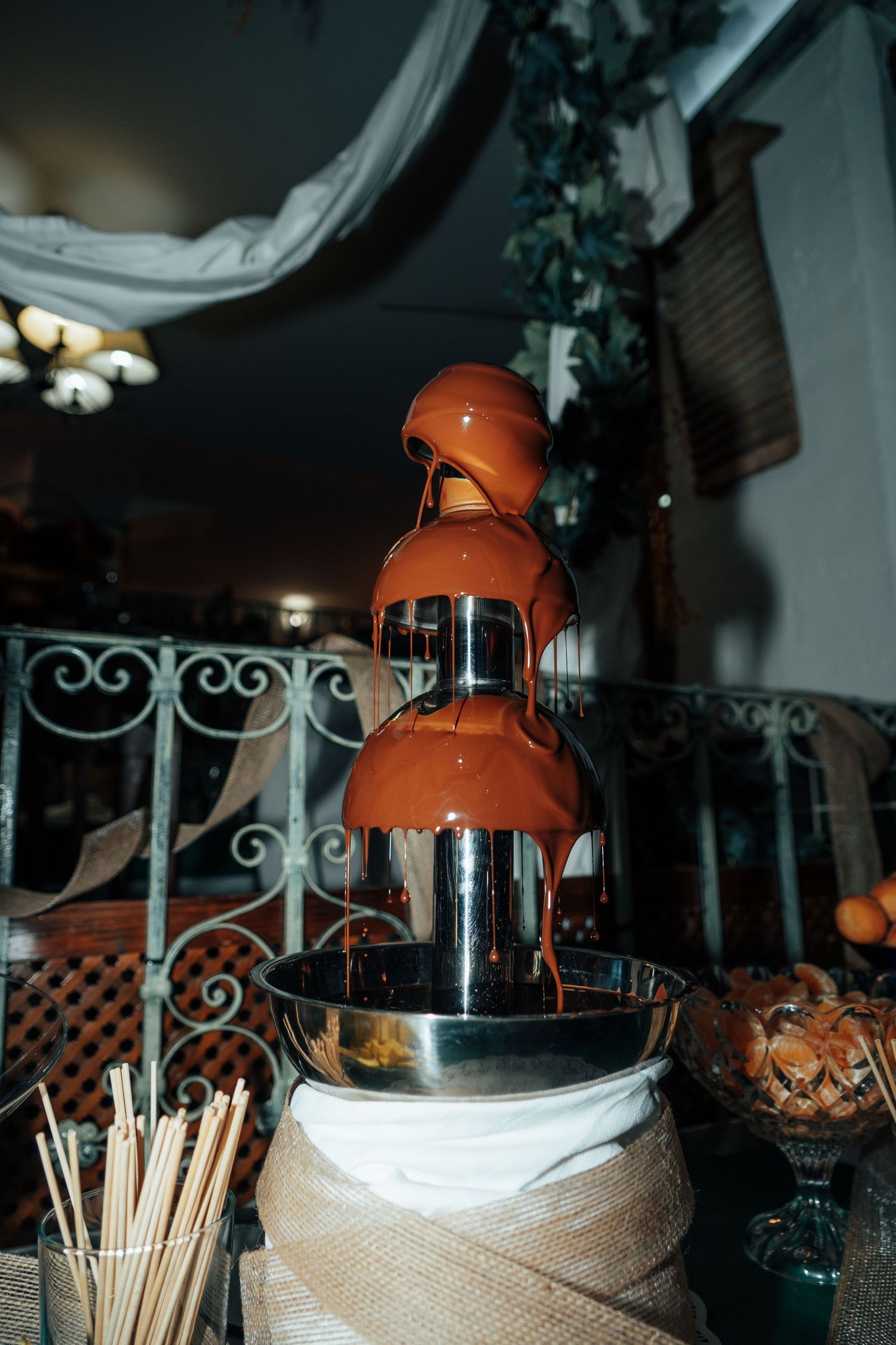 Elegant chocolate fountain with flowing melted chocolate tiers at a wedding reception dessert table.