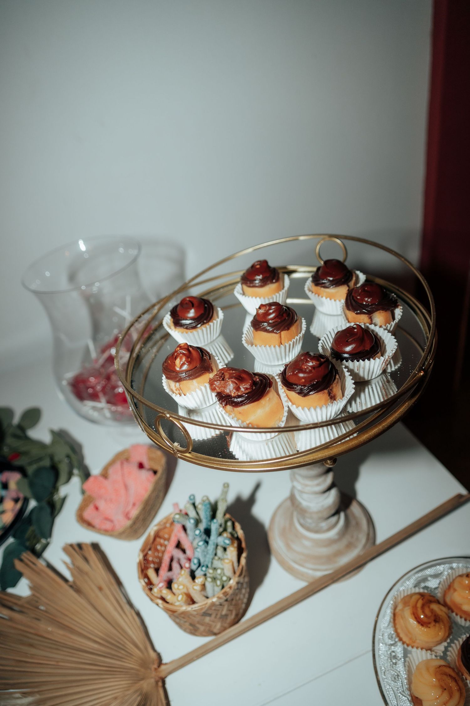 Elegant dessert display with chocolate-topped cupcakes on a gold cake stand at a party.