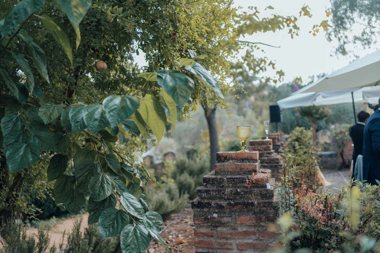 Rustic brick garden pathway lined with lush greenery at an outdoor wedding venue.