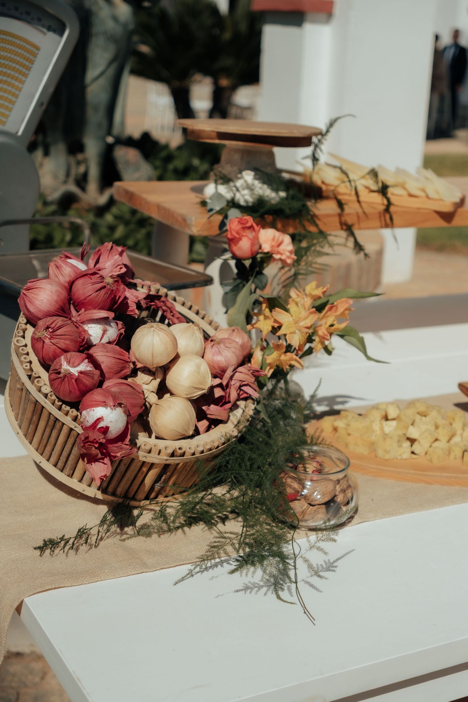 Elegant wedding reception table displaying basket of colorful onions and flowers as rustic decor.