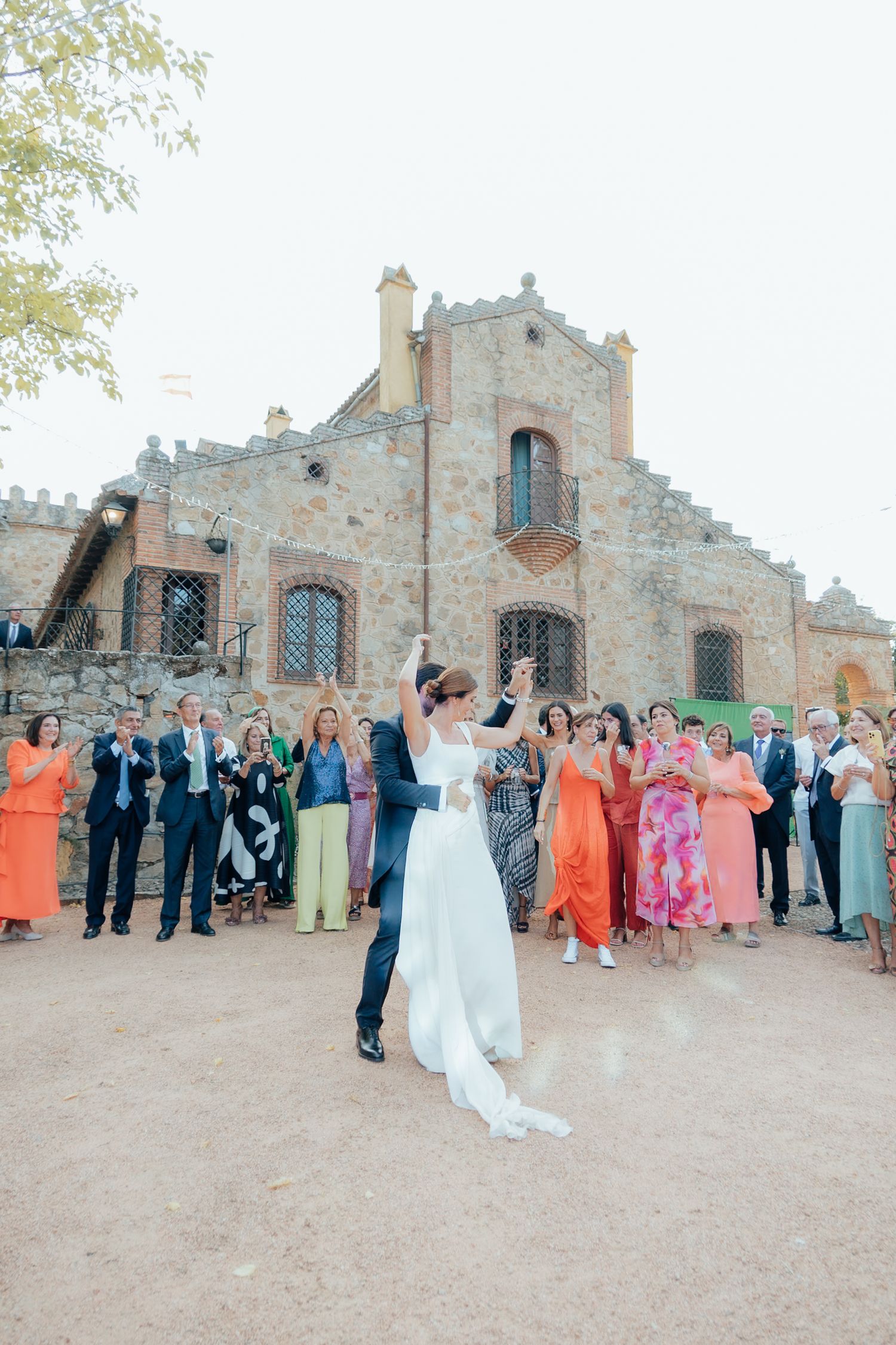 Bride and groom celebrating with guests outside historic stone castle wedding venue.