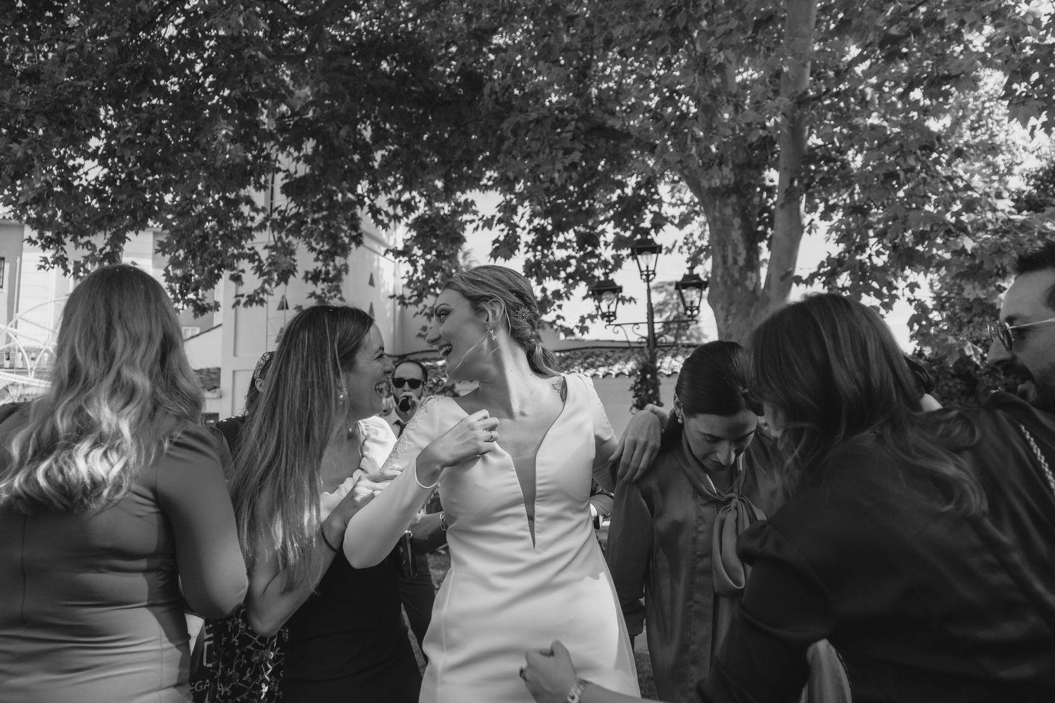 Black and white photo of bride sharing emotional moment with female guests at wedding.