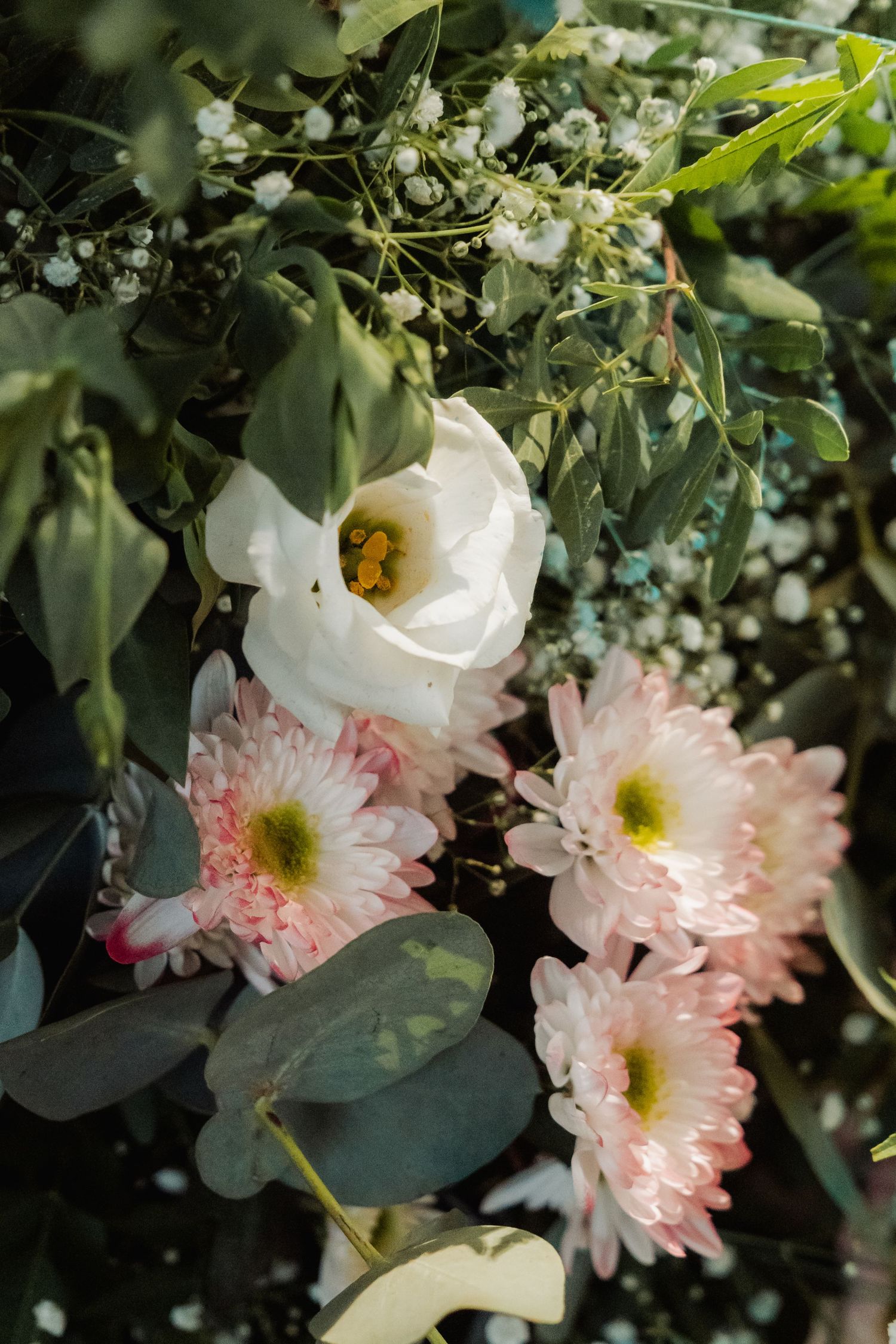 Beautiful wedding floral arrangement featuring white lisianthus and pink chrysanthemums with greenery.