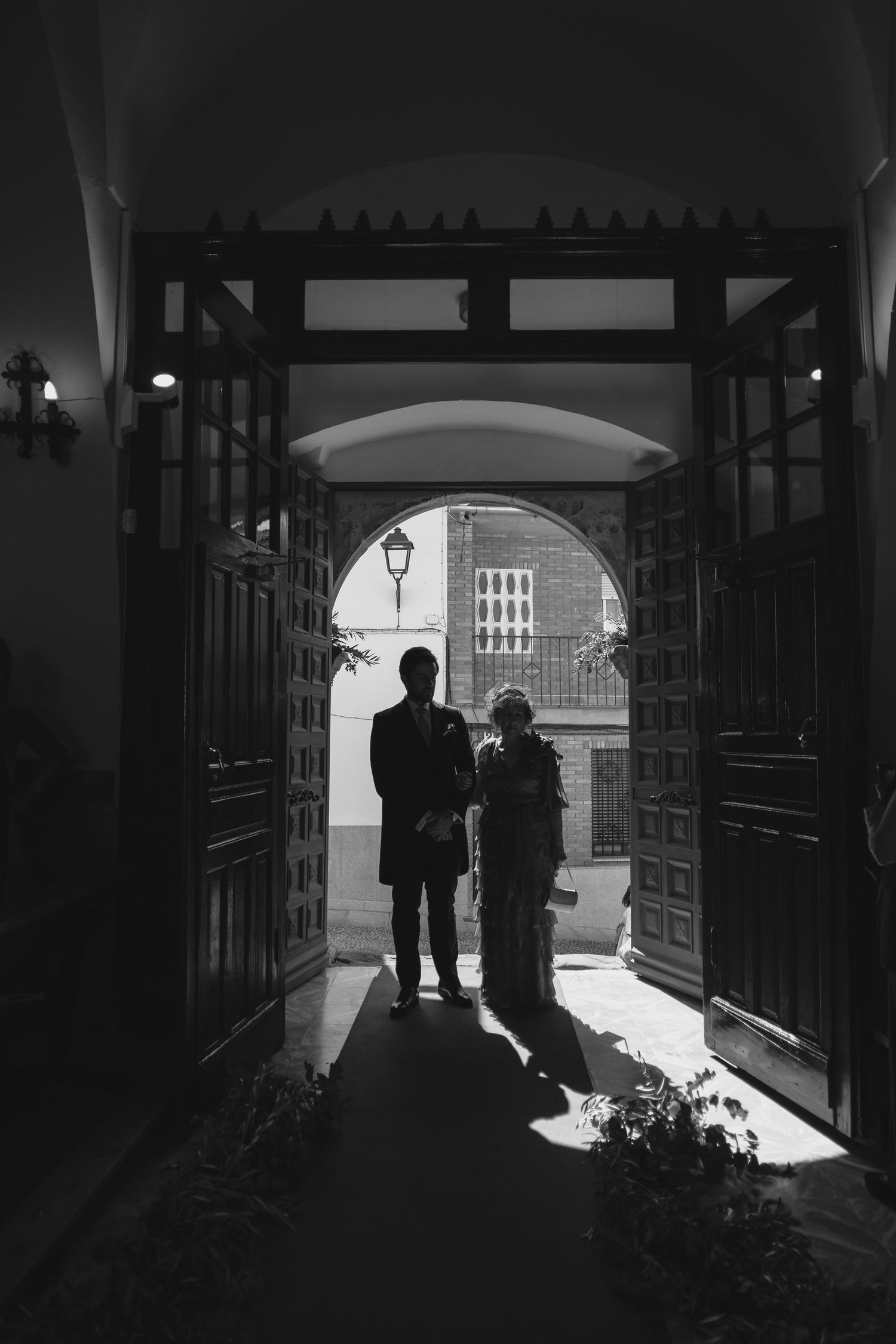 Silhouette of couple standing in ornate church doorway in black and white wedding photography.