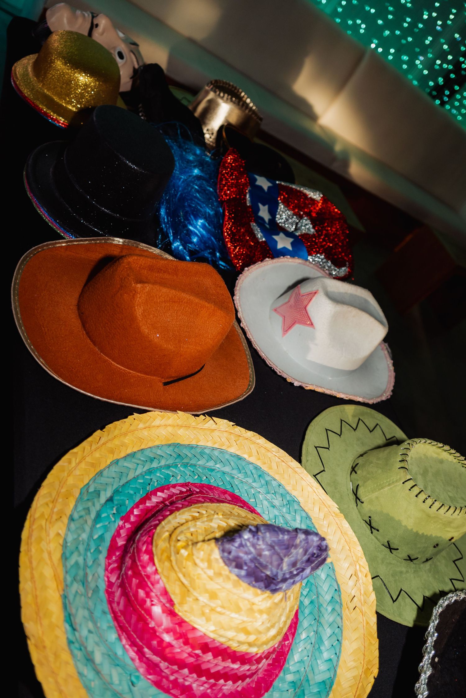 Colorful collection of novelty cowboy hats and sombreros displayed on a dark surface at a party.