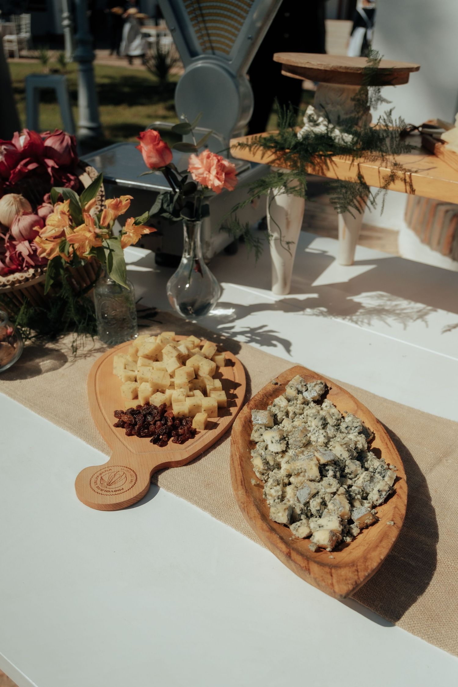 Rustic wooden boards displaying blue cheese and cubed cheese at an elegant outdoor wedding reception.