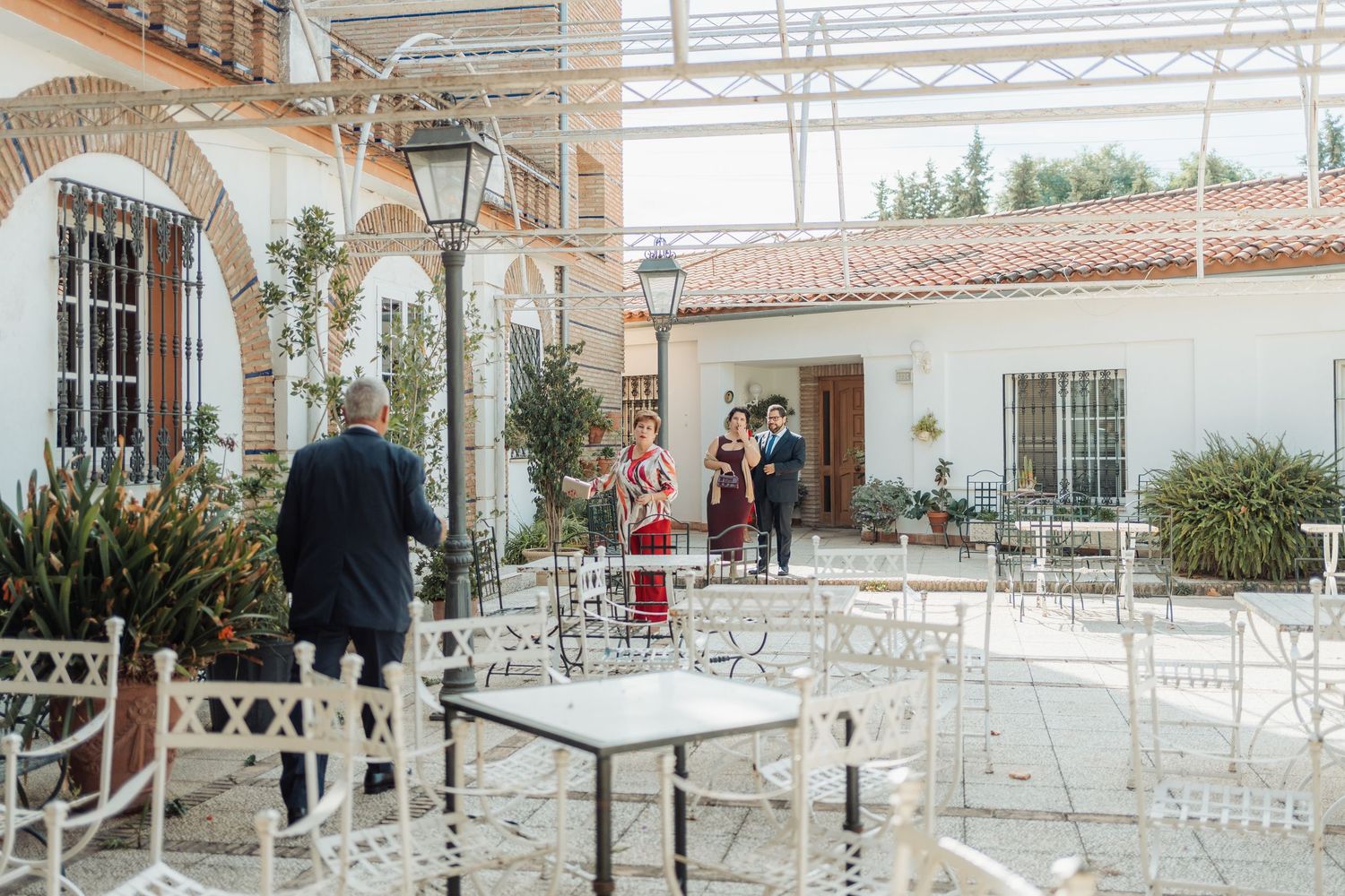 Guests mingling in a sunlit white courtyard patio at an elegant wedding venue.