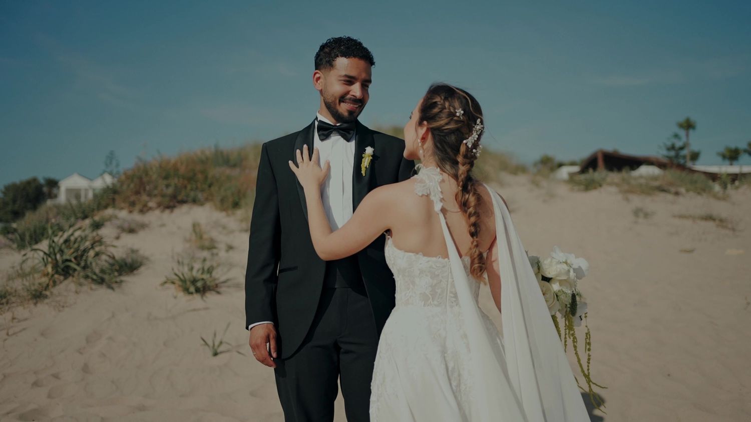 Bride and groom share a tender moment on a sandy beach on their wedding day.