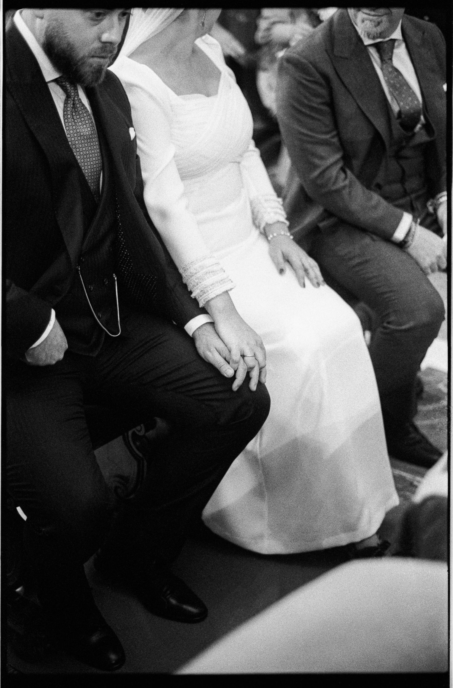 Bride and groom holding hands in black and white wedding ceremony photo.