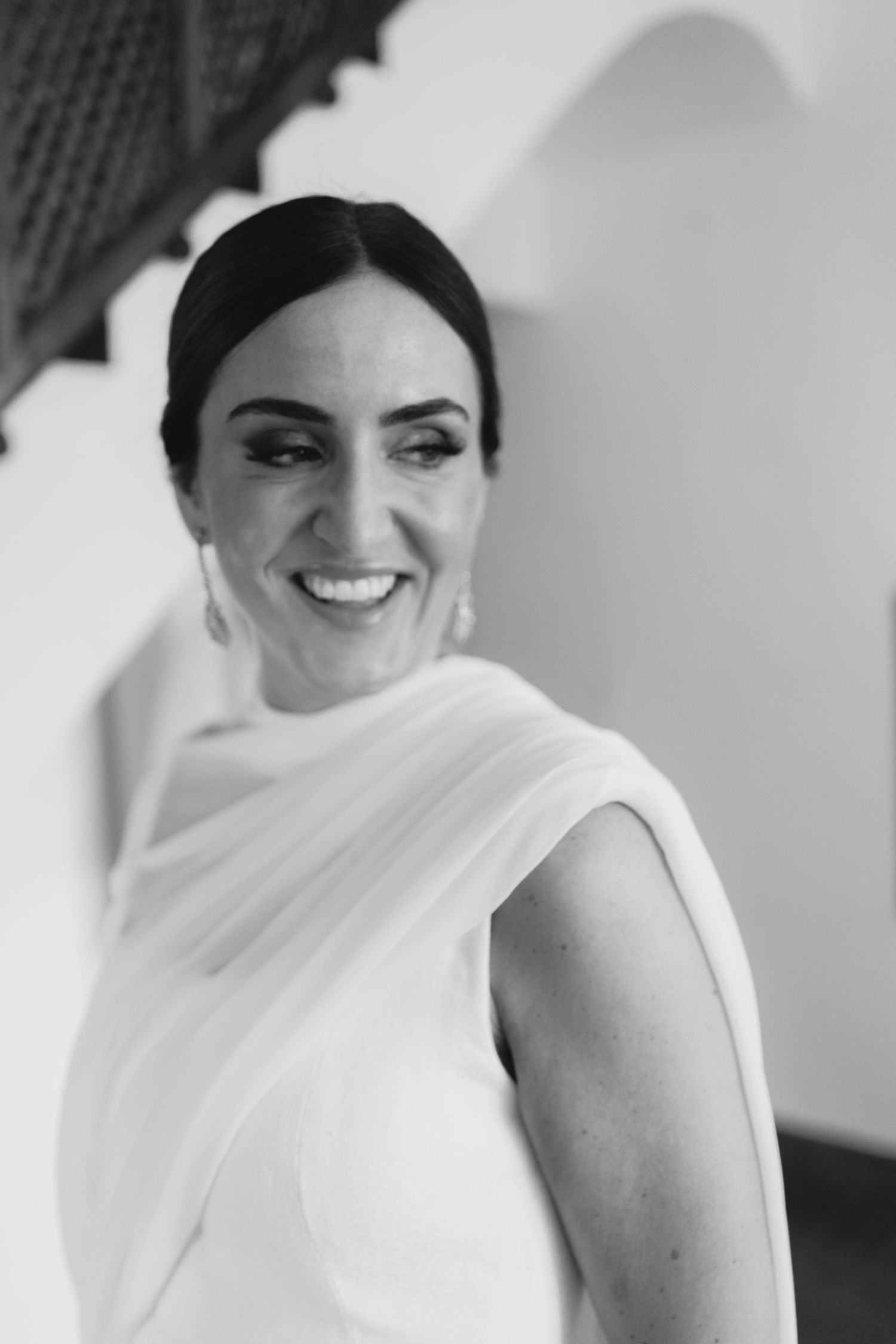 Black and white portrait of smiling bride in white draped wedding gown looking radiant.