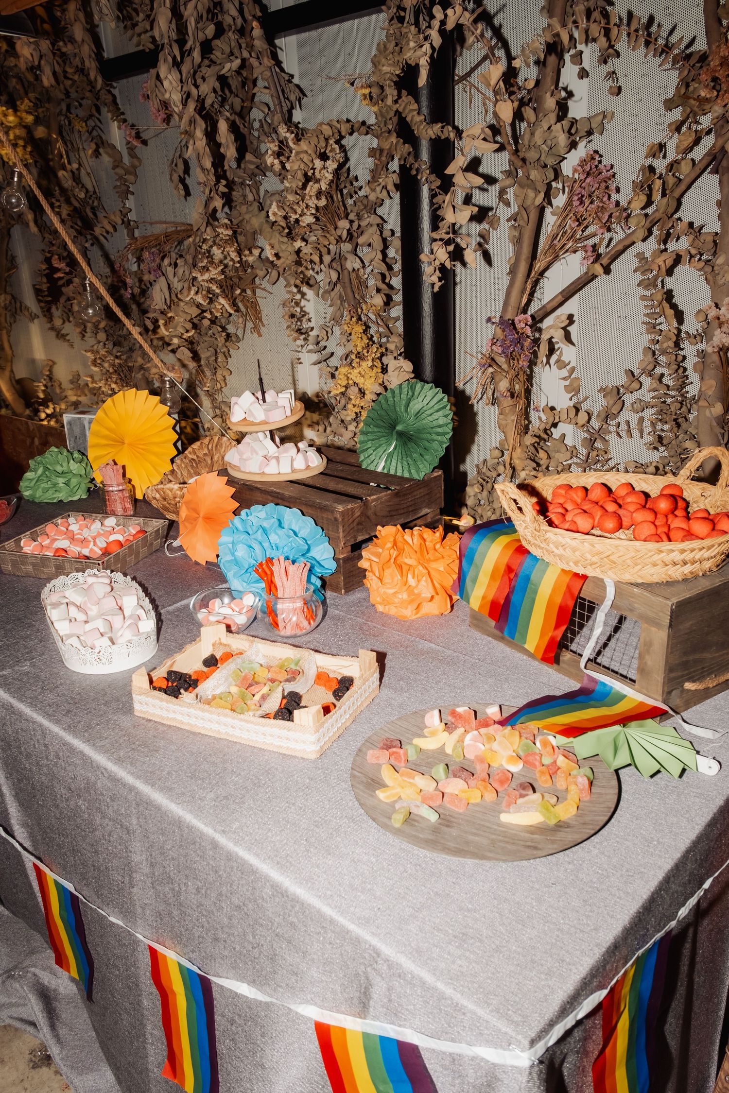 Elegant candy bar table decorated with rainbow bunting and filled with assorted sweets and treats.