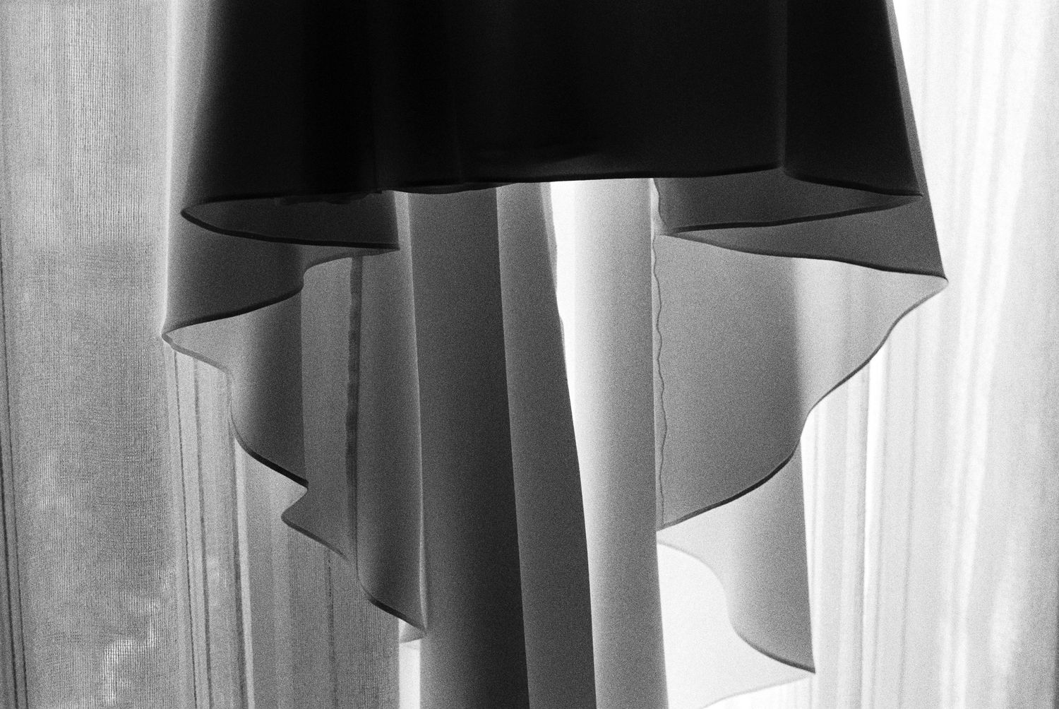 Black and white close-up of layered bridal veil fabric with soft light filtering through curtains.