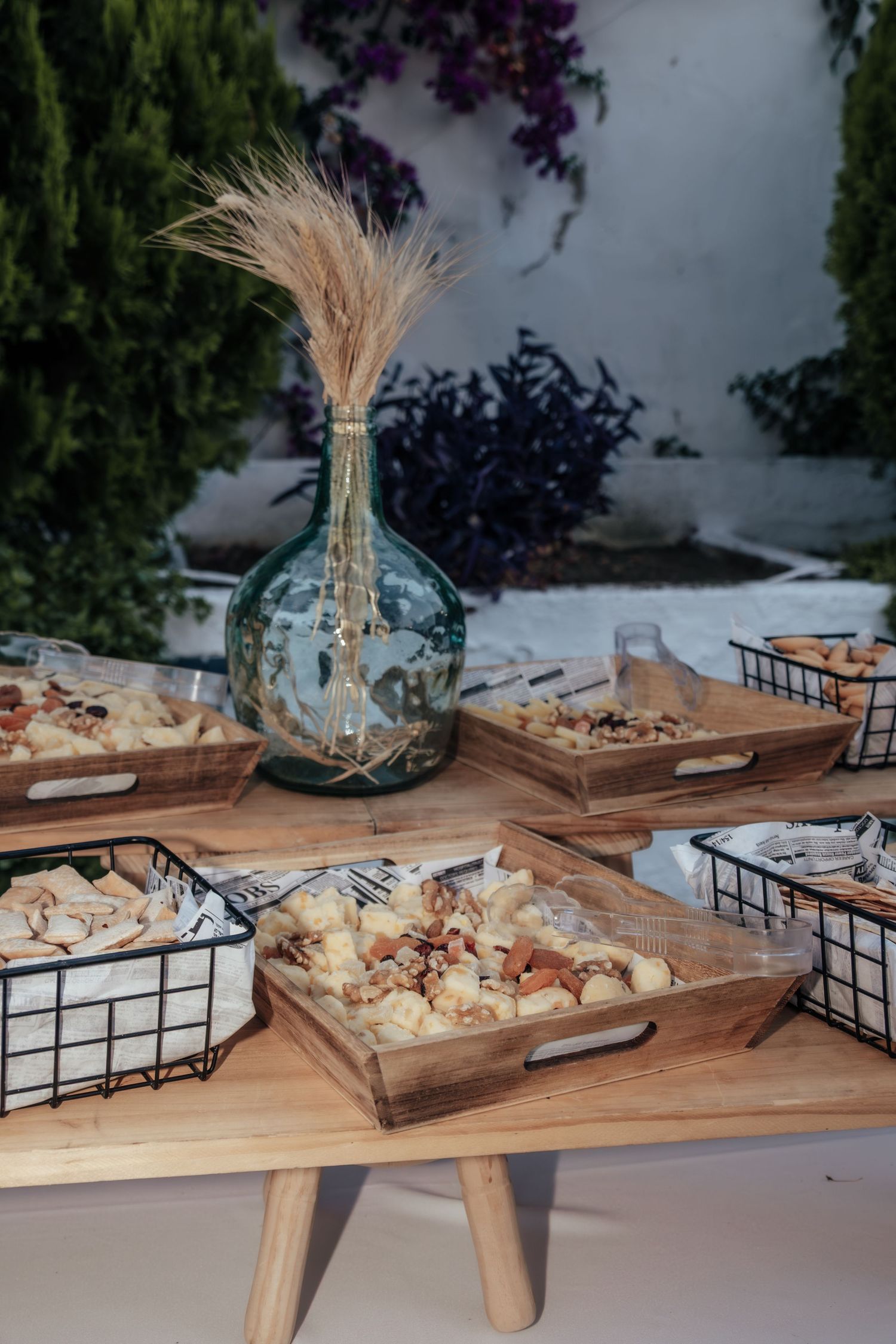 Elegant wedding reception snack table with nuts, appetizers, and decorative glass vase.