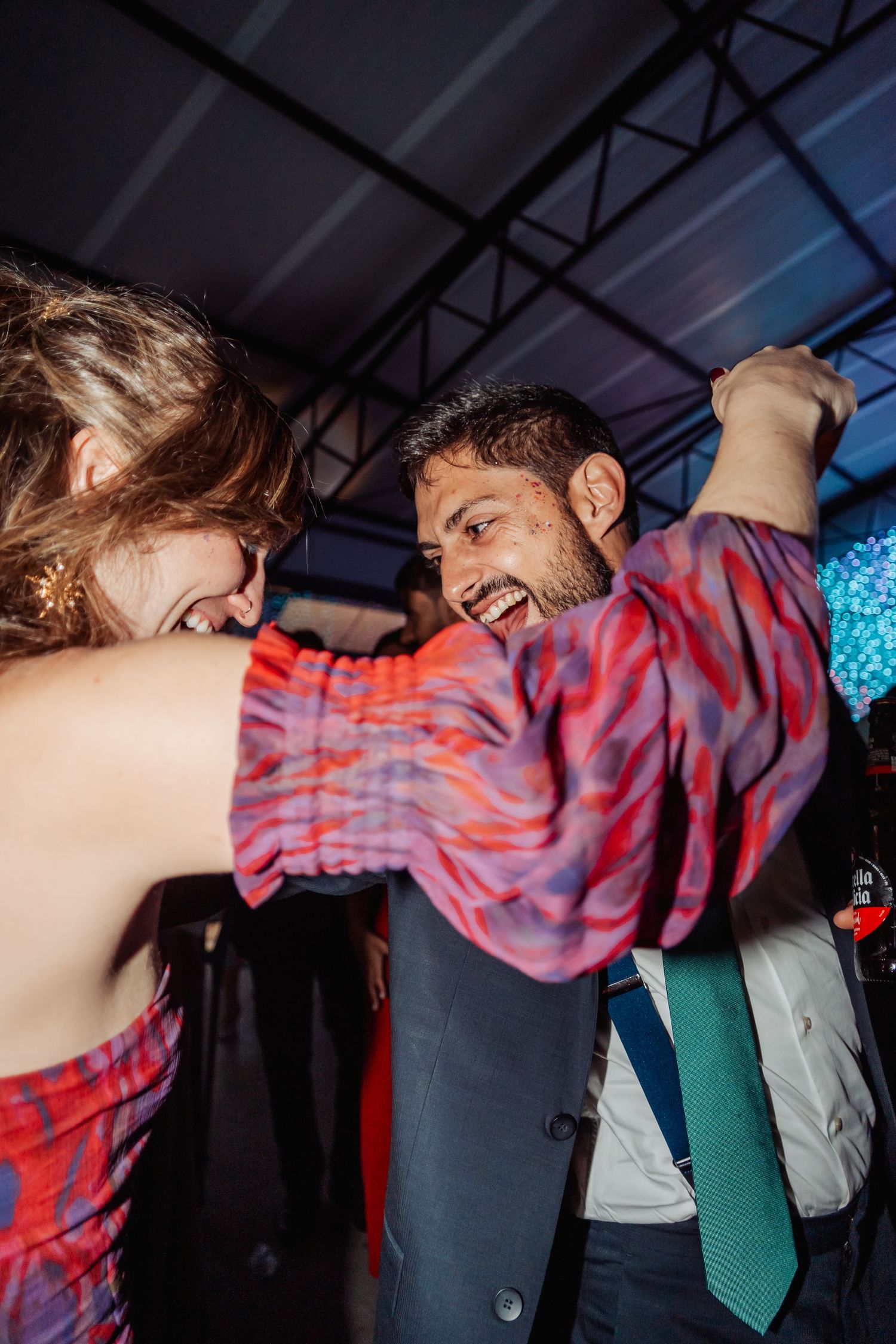 Joyful couple laughing and dancing together energetically at a vibrant wedding reception party.