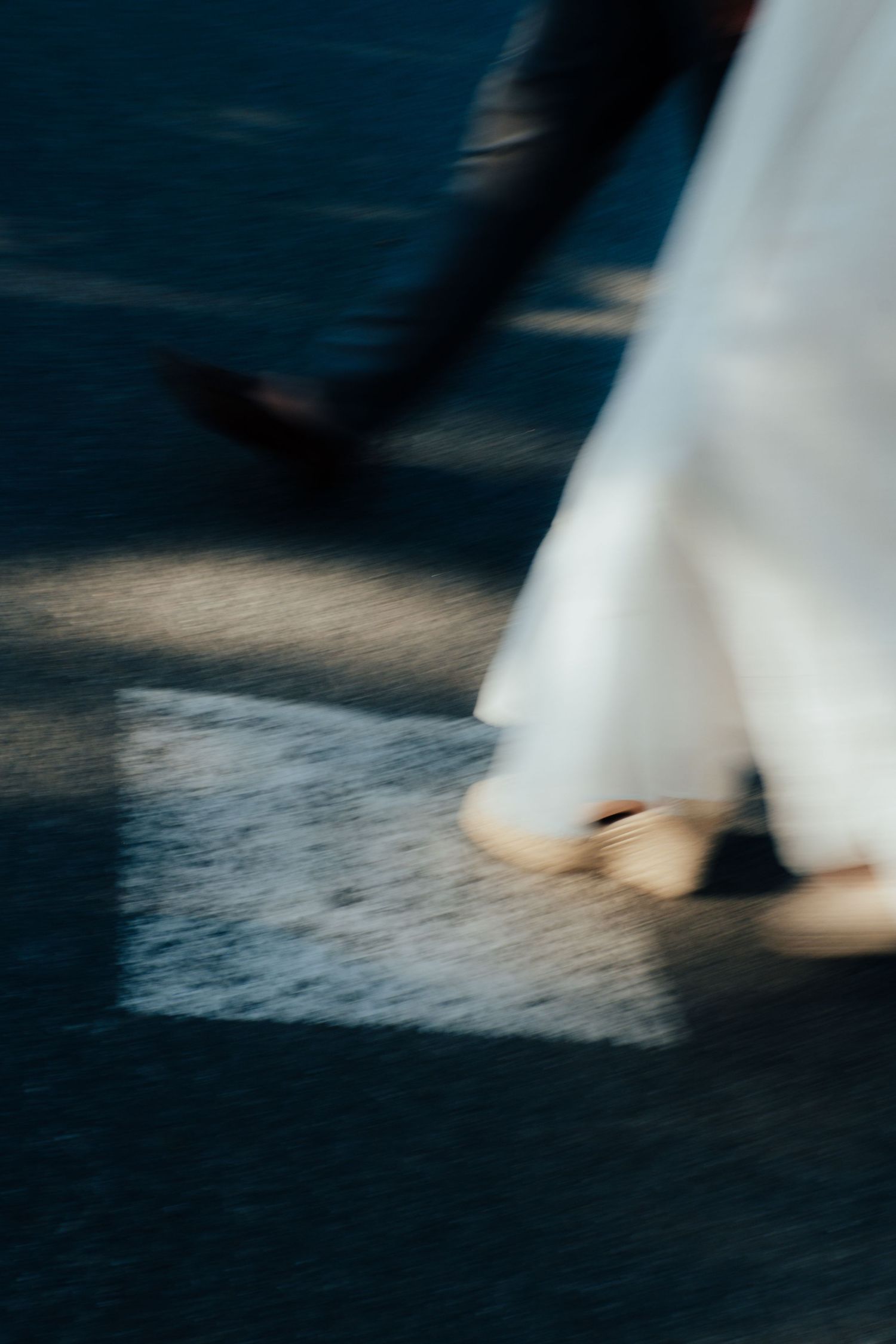 A motion-blurred artistic shot of a bride and groom walking, capturing the movement of their feet and dress.