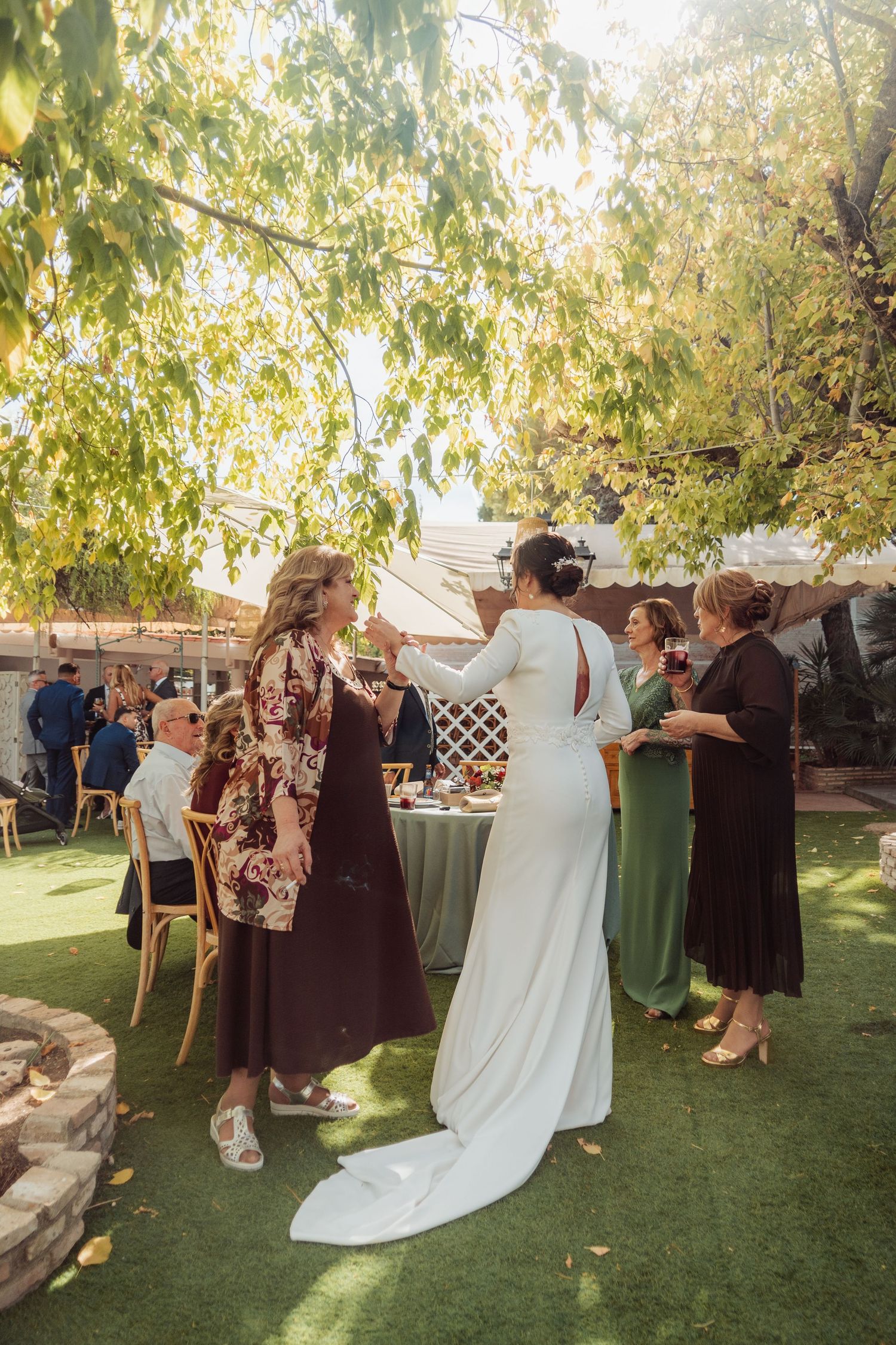 Bride in white gown socializing with guests at outdoor garden wedding.