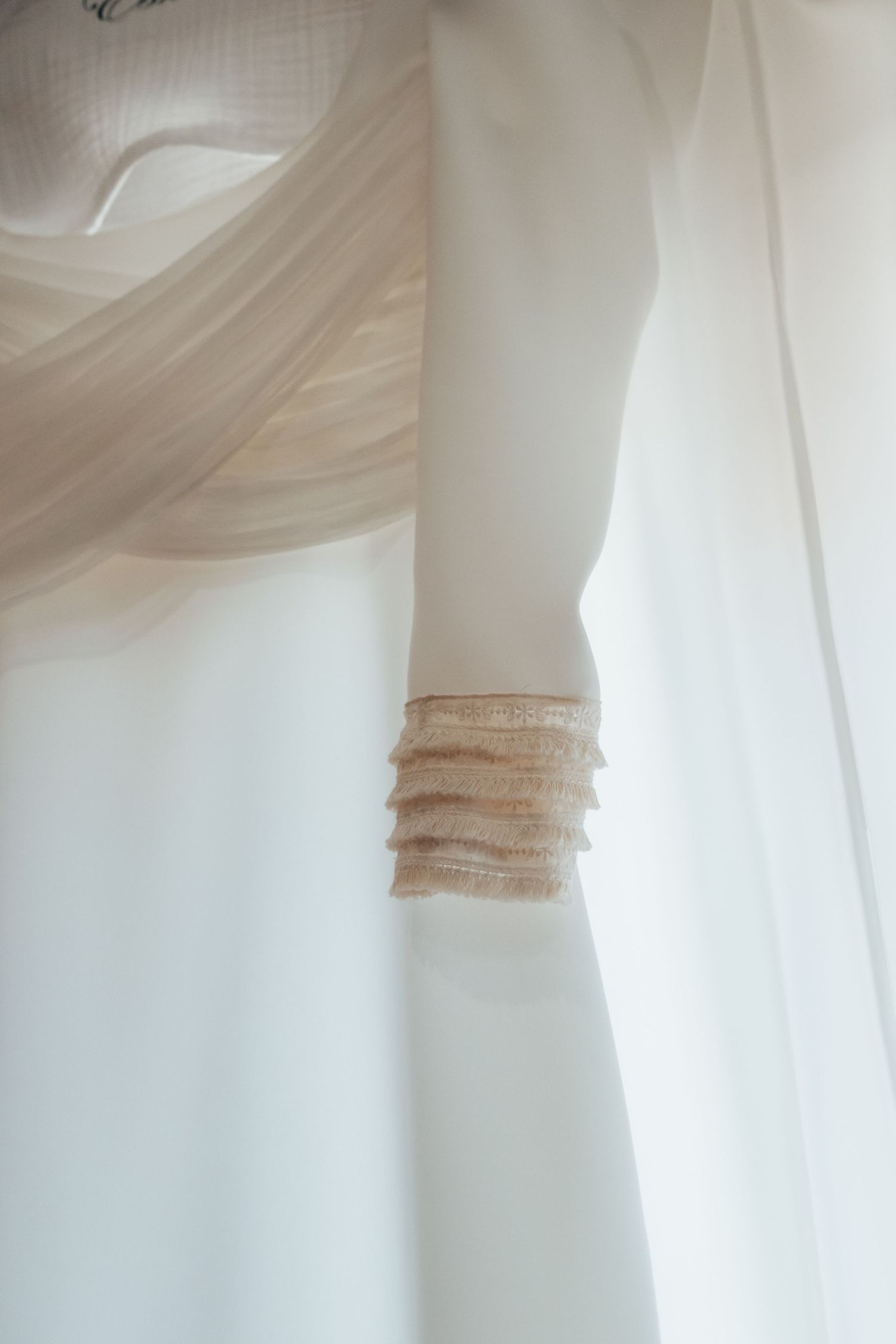 Close-up detail of delicate ruffled trim on elegant ivory wedding dress sleeve.