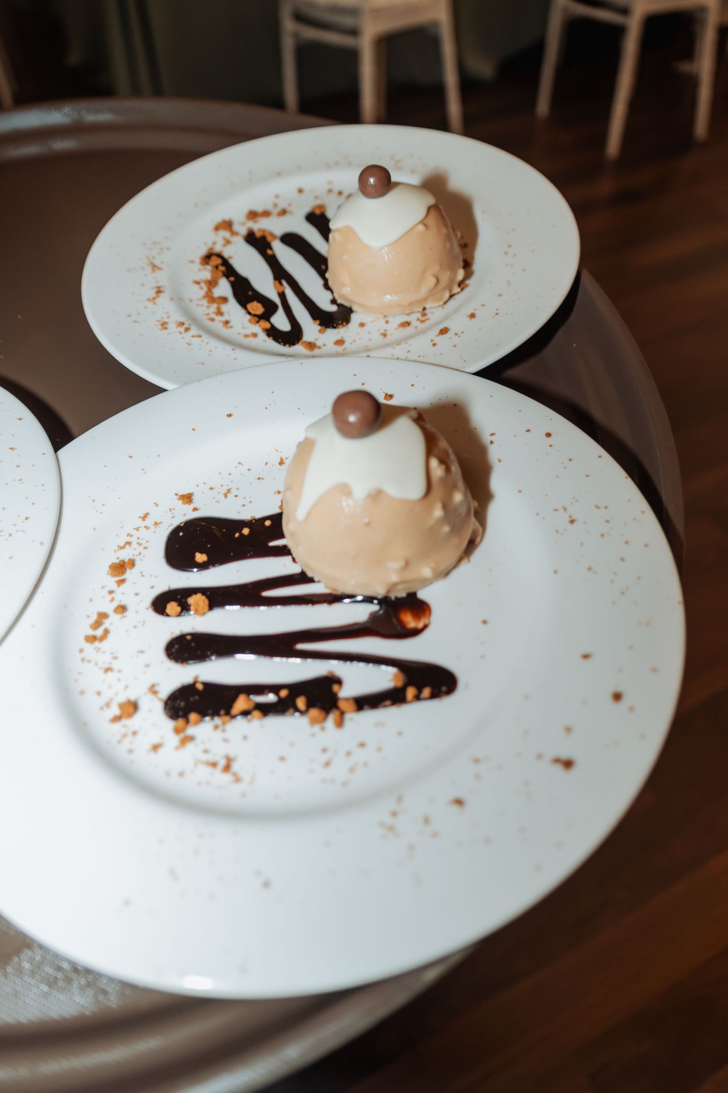 Elegant chocolate mousse desserts with chocolate sauce drizzle served on white plates at a wedding.