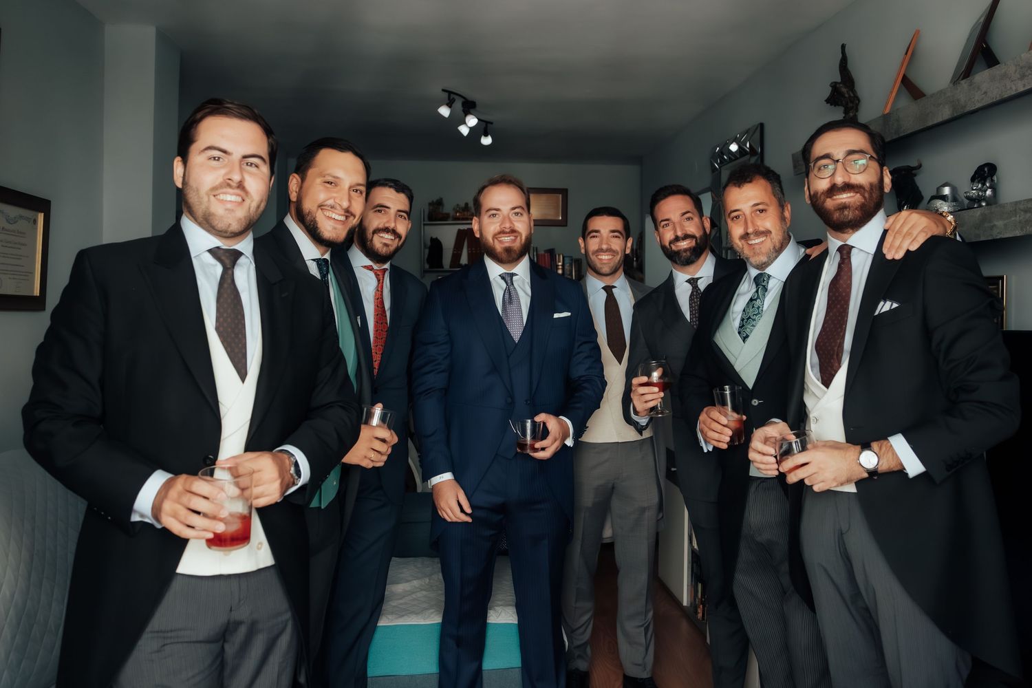 Group of groomsmen in suits smiling and celebrating together before wedding ceremony.