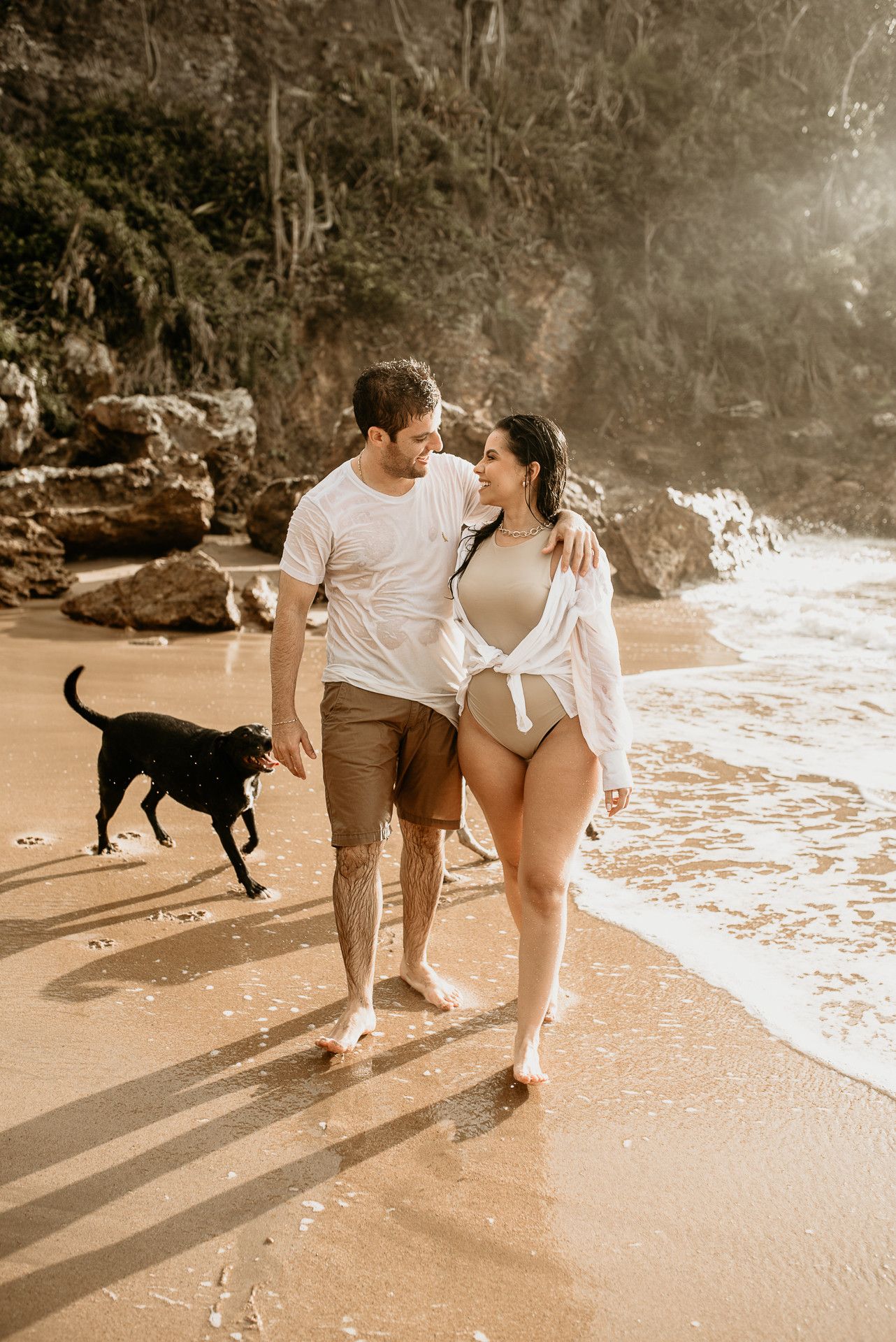 Caminhando descalços na areia da praia em Búzios durante o pôr do sol, sorrindo um para o outro.
