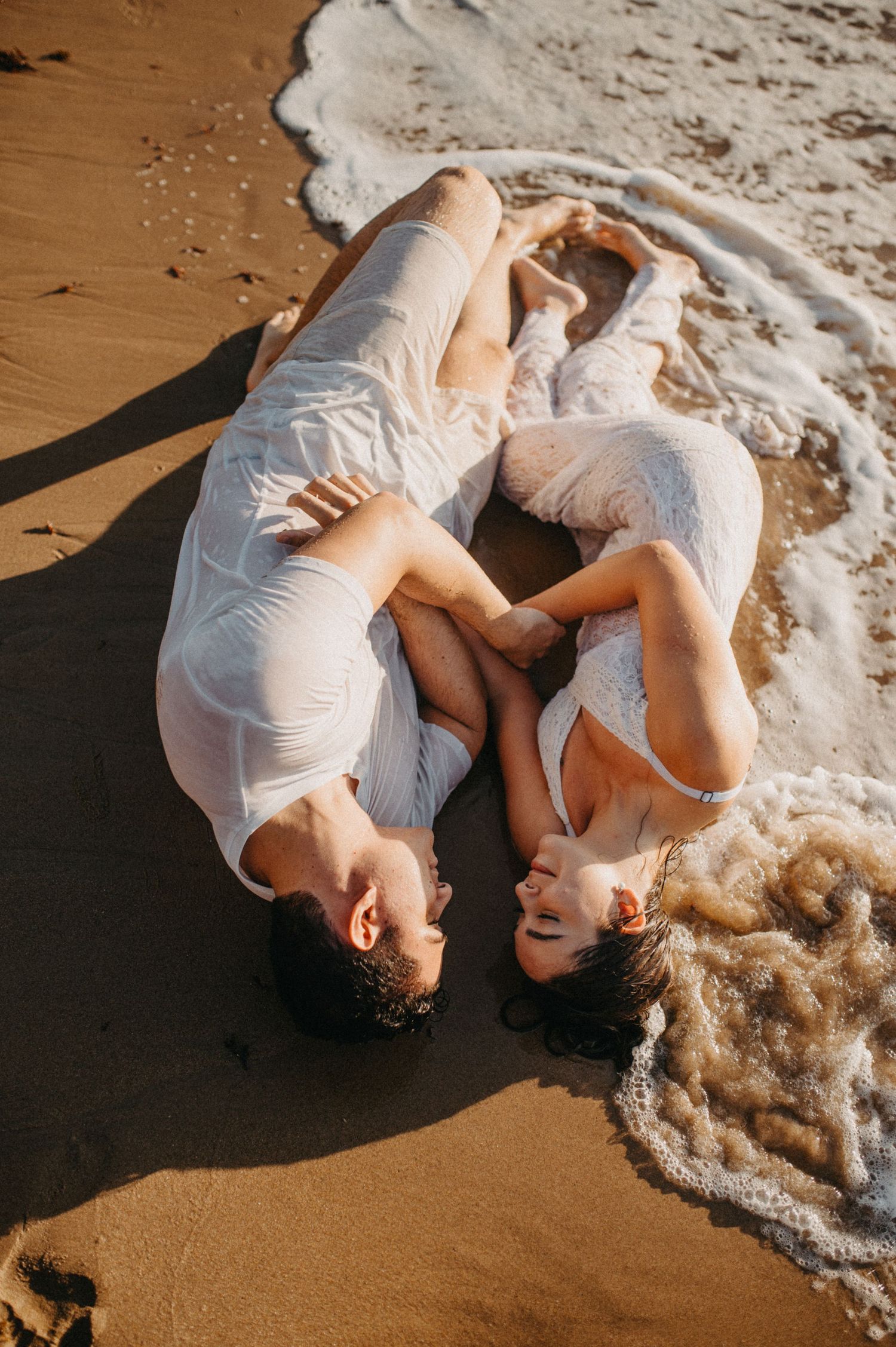 Casal Bruno e Magale se beijando apaixonados sentados na areia molhada durante ensaio pre wedding na praia do Pai Vitório em Búzios - RJ