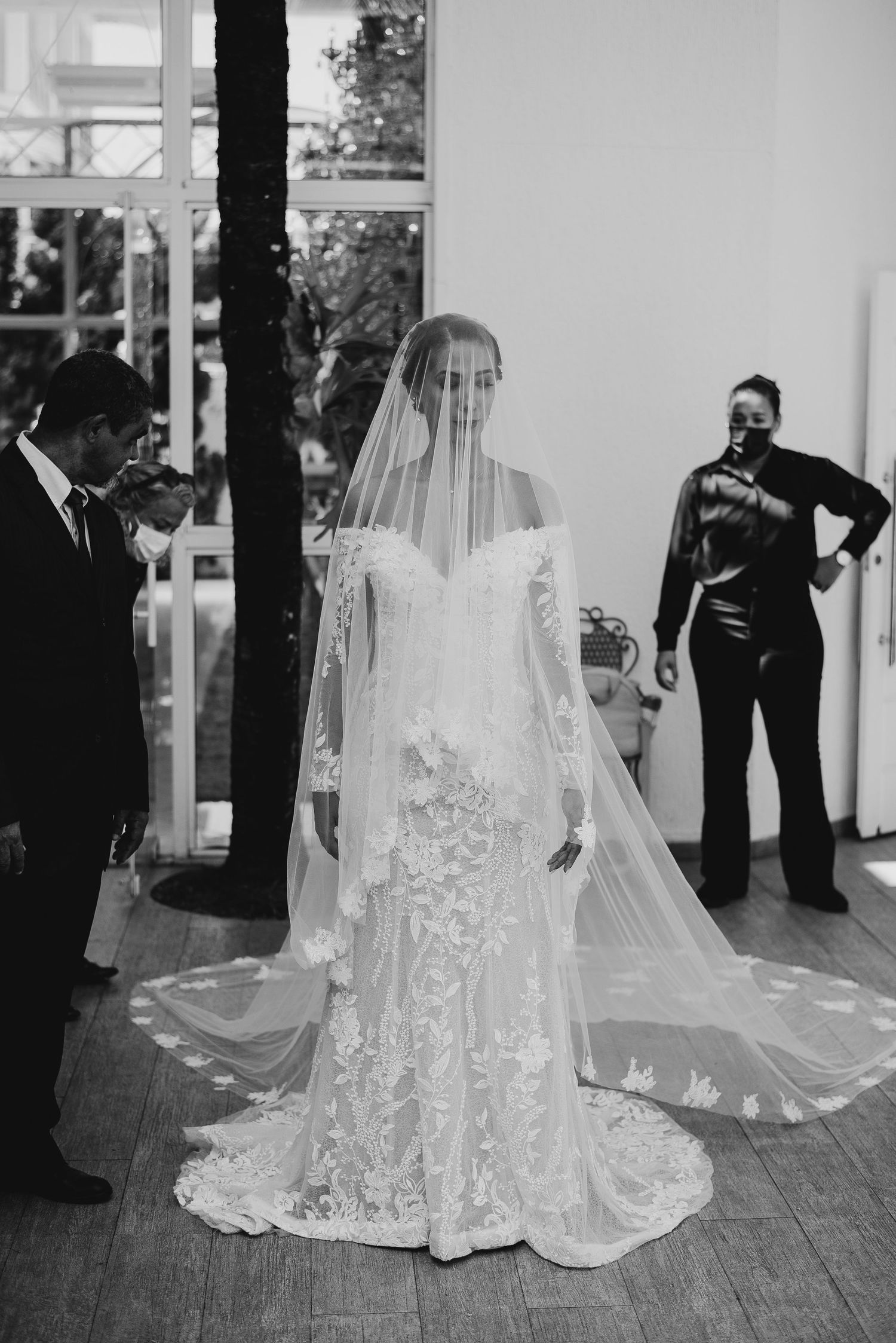 vestido de noiva de renda detalhado e um longo véu cobrindo o rosto, transmitindo serenidade e elegância antes da entrada em Rio das Ostras