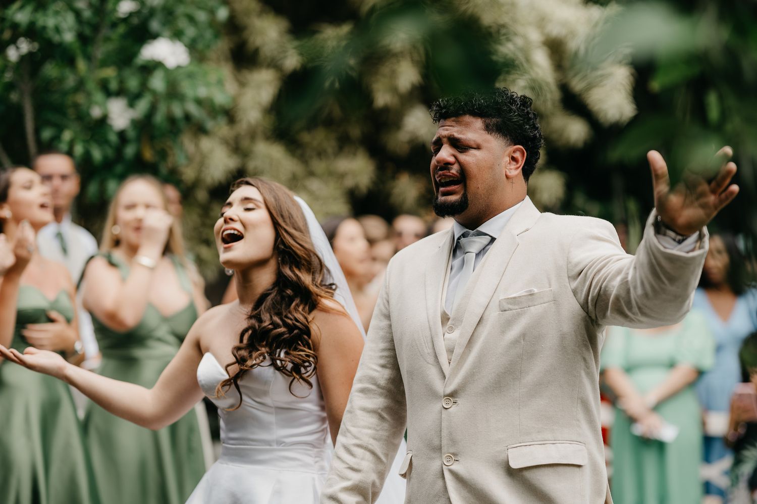 Noivos chorando e cantando com convidados em verde oliva, casamento ao ar livre no Sítio Catavento em Araruama, Rio de Janeiro.