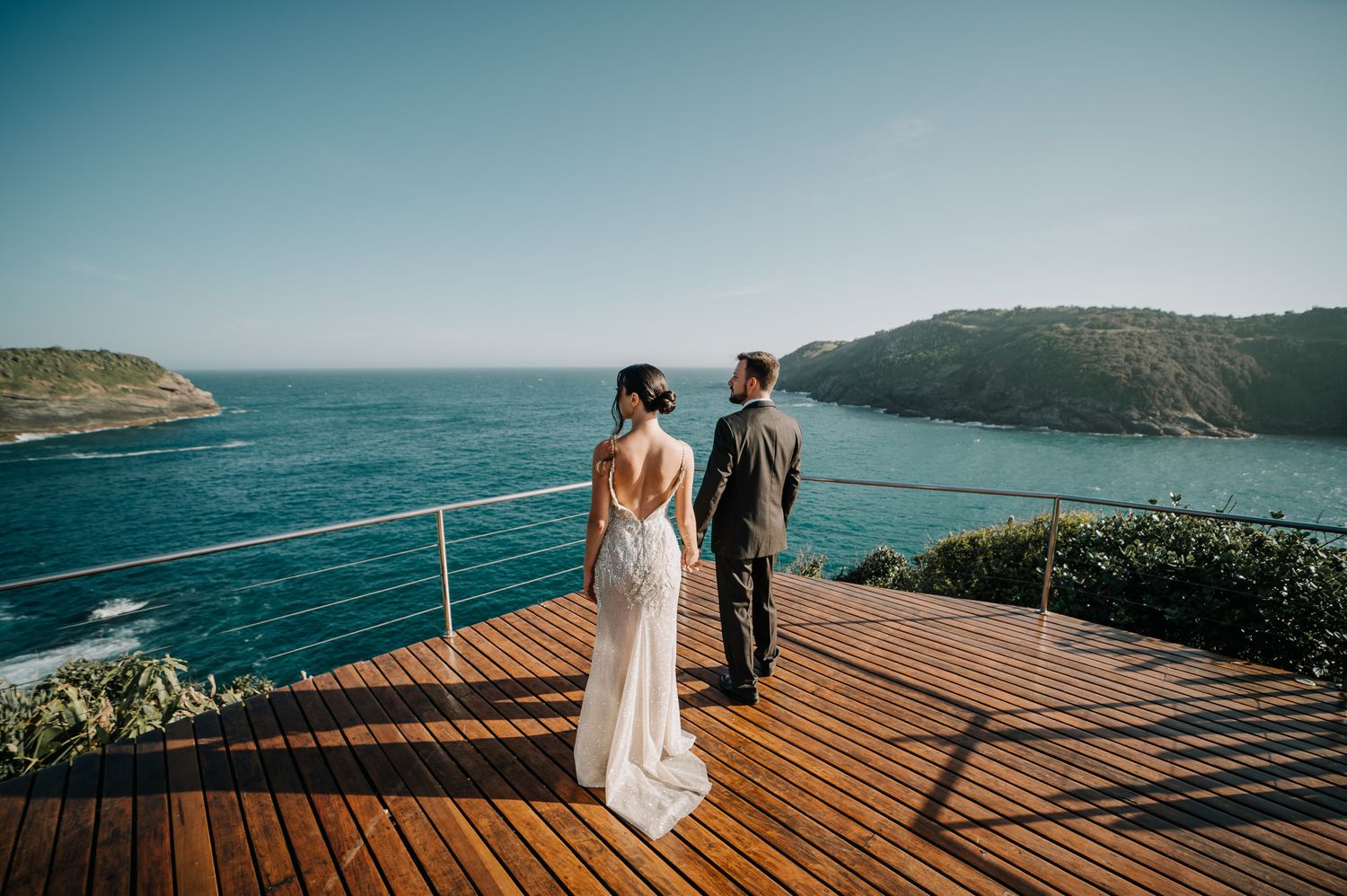 Fotografia de destination wedding em cliffside, Buzios, RJ, casal de noivos olhando a vista panorâmica do mar