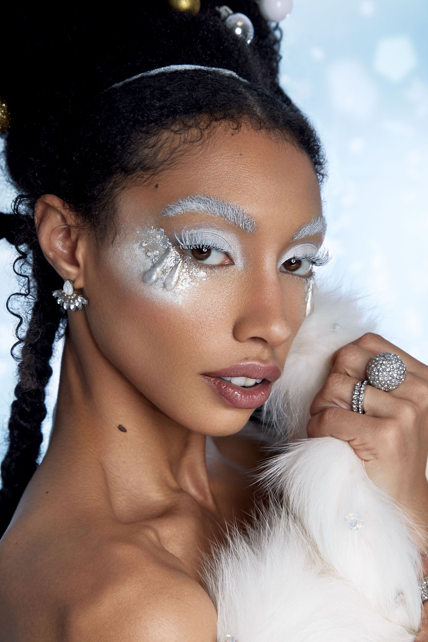 Winter beauty portrait featuring silver glitter eye makeup and white fur accessories.