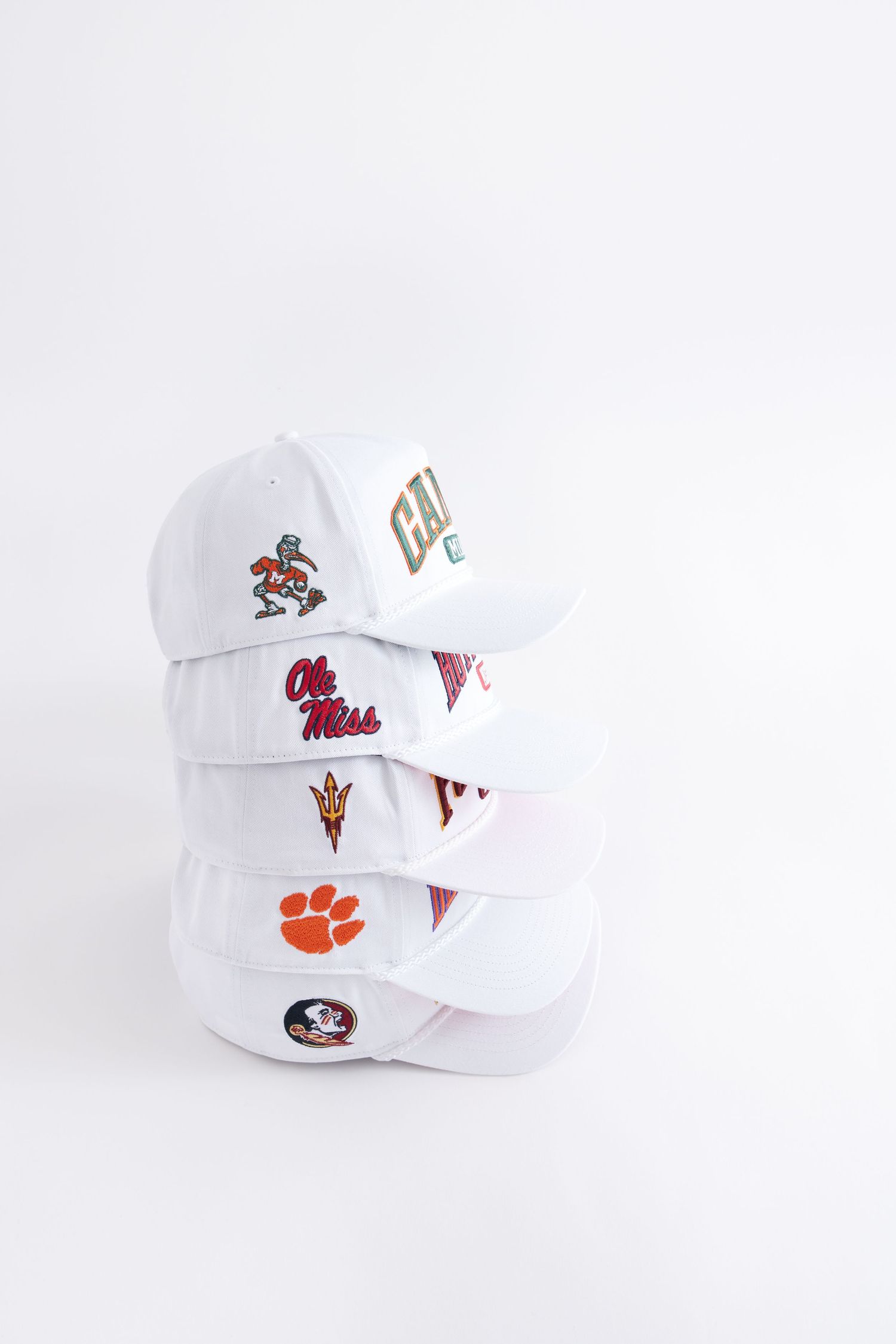 White baseball caps with college sports team logos and mascots displayed from different angles.