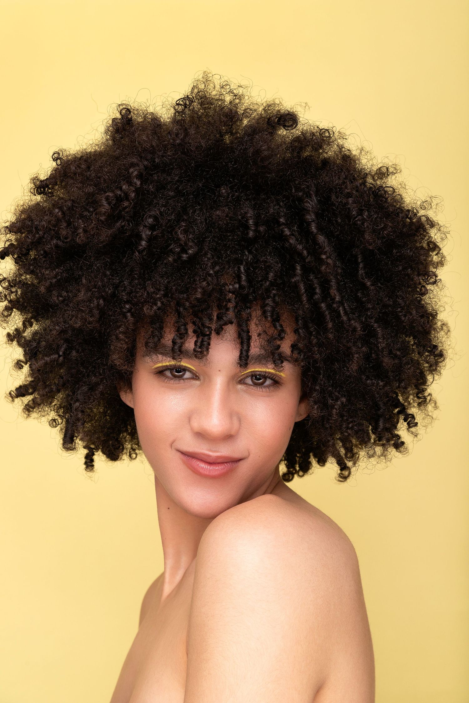 A portrait series showing natural curly hair against a warm yellow background.
