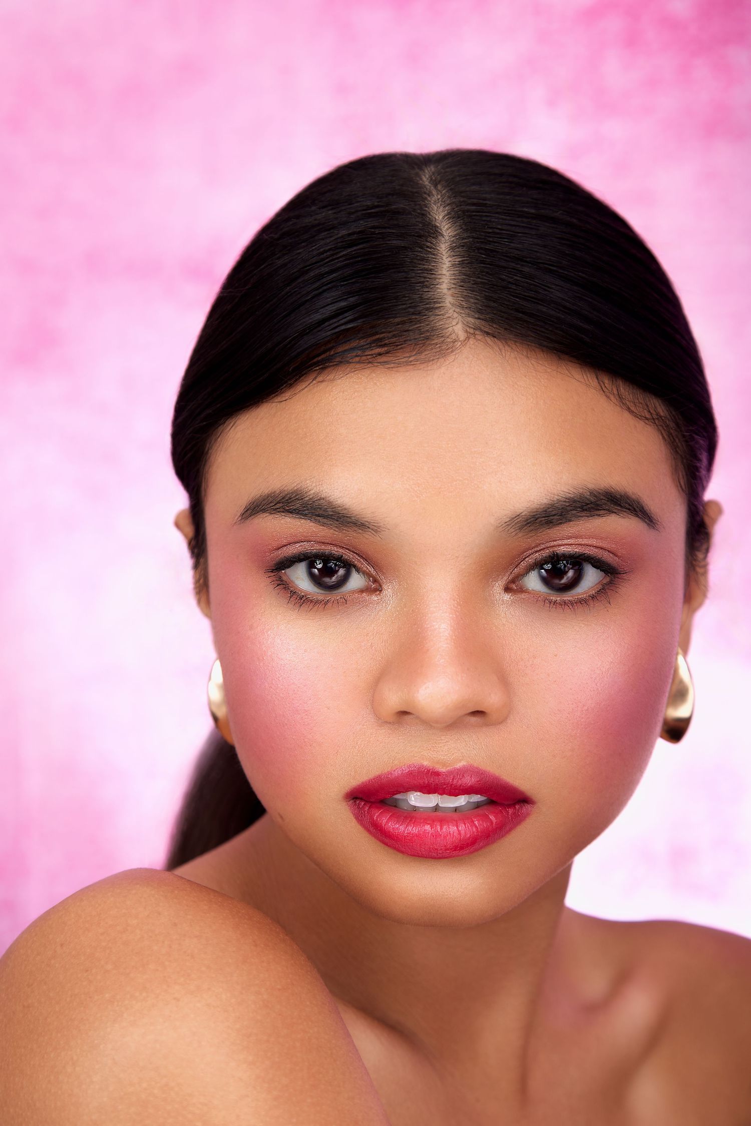 Artistic beauty portrait with pink background showing glamorous makeup and red lipstick.