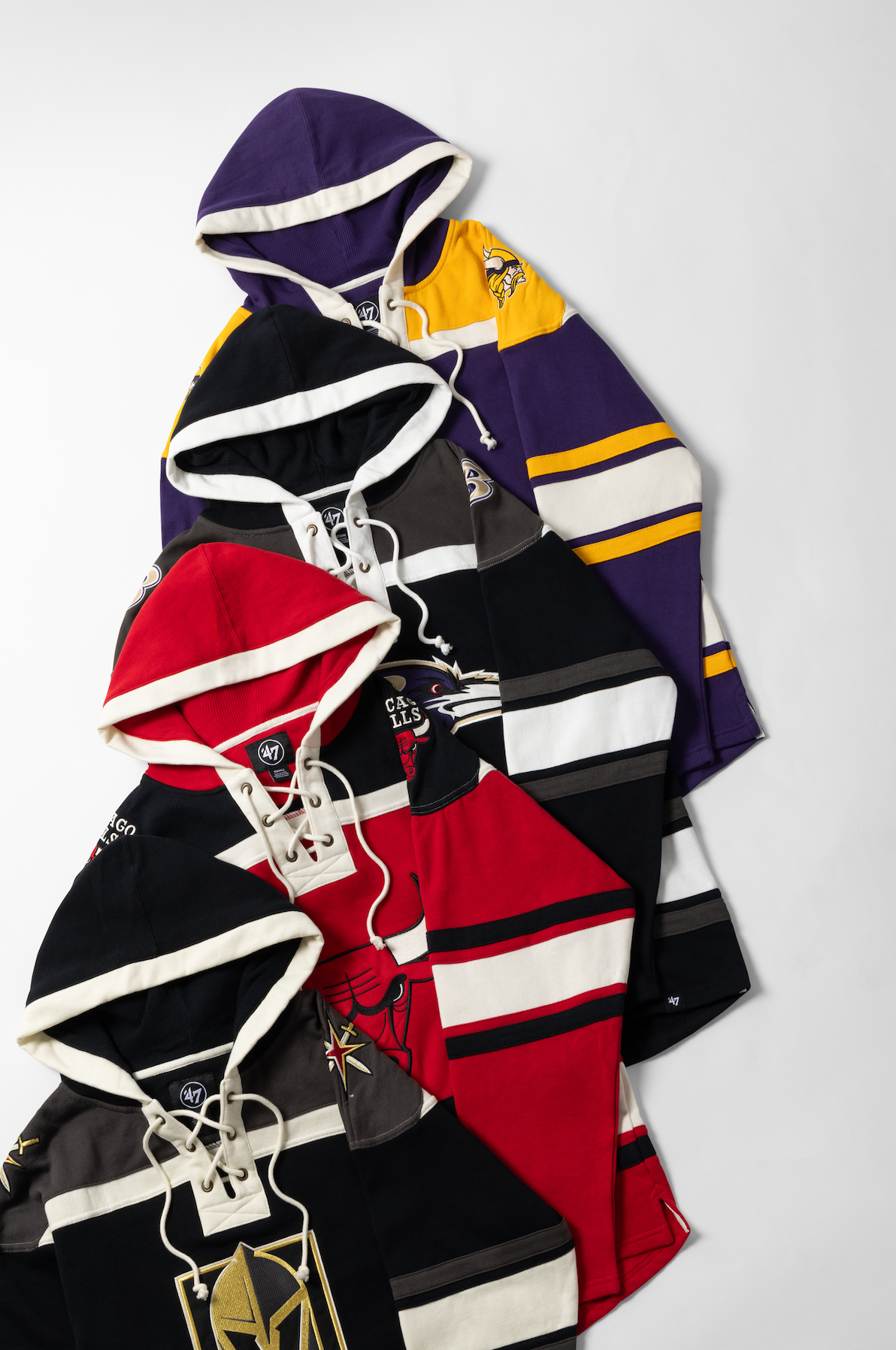 A collection of folded hockey jerseys in various team colors including purple, red, black, and yellow displayed together.